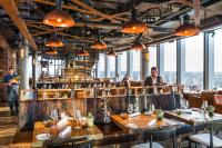 a restaurant with wooden tables and people in the background at Novotel London Canary Wharf in London