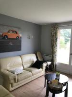 a living room with a white couch and an orange car on the wall at Gite du Crinchon in Rivière