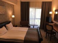 a hotel room with a bed and a chair and a window at Hotel Arnia in Iaşi