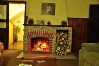 a living room with a fireplace with logs in it at Pousada Sino dos Ventos in Campos do Jordão