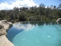 a large pool of blue water with trees in the background at Mas de la Fariole in Caixas