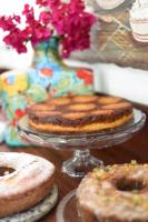 two cakes on plates on a table with donuts at Pousada Casa do Catavento in Búzios