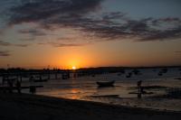 a sunset on a beach with boats in the water at Pousada Casa do Catavento in Búzios