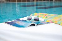 ein Spielzeugflugzeug auf einer Zeitschrift neben einem Pool in der Unterkunft U Coral Beach Club Eilat – Ultra All inclusive in Eilat