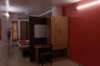 Habitación con mesa, silla y pared roja. en Hotel Pariwar, en Aurangabad