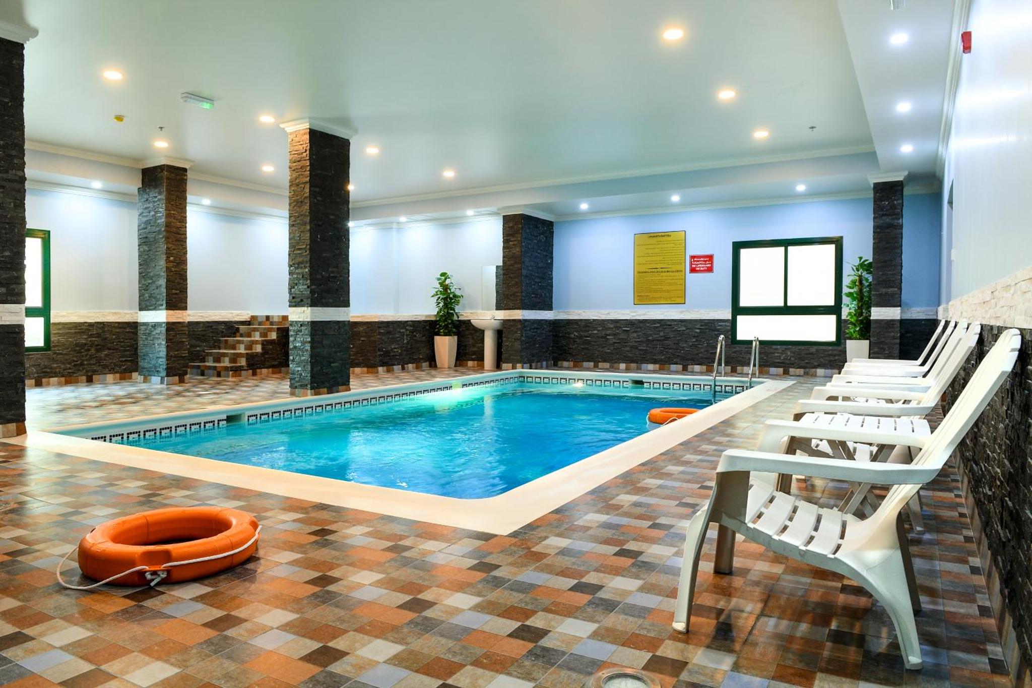 a pool in a hotel with two chairs and a swimming pool at Montana Tower in Manama