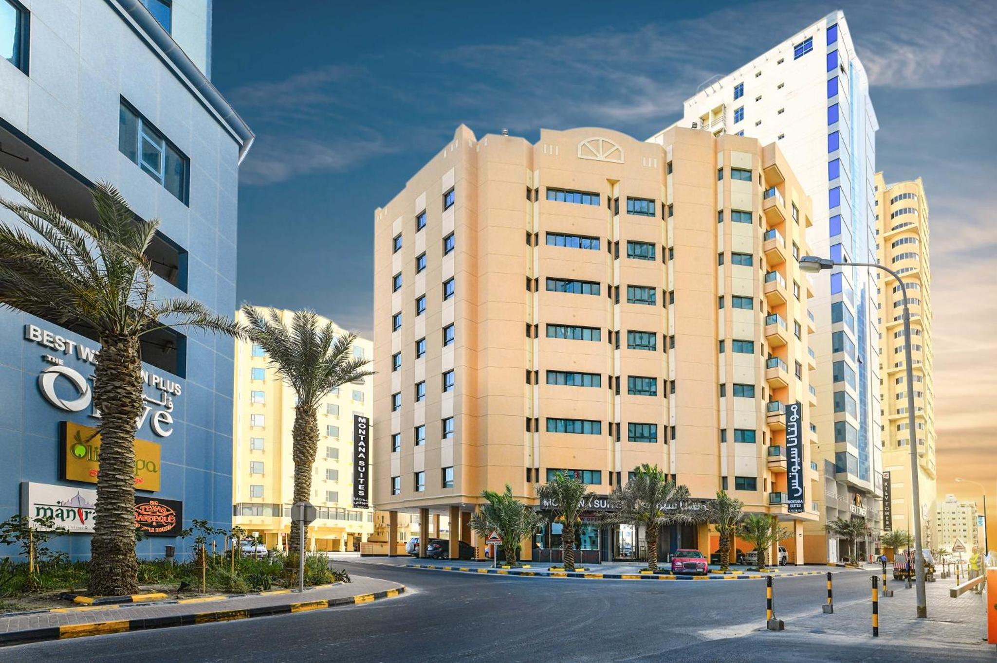 a building in a city with palm trees and buildings at Montana Tower in Manama