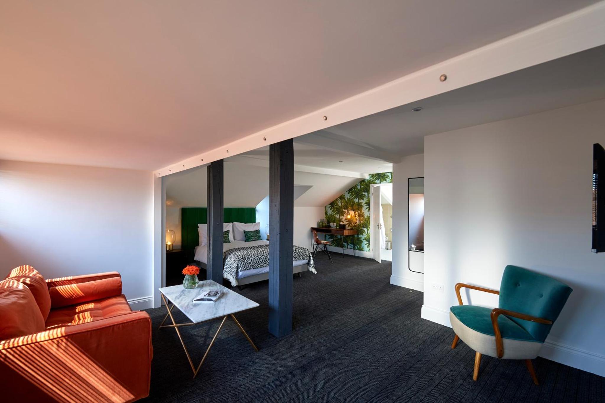 a living room with a couch and a bed at The Lodge Hotel - Putney in London