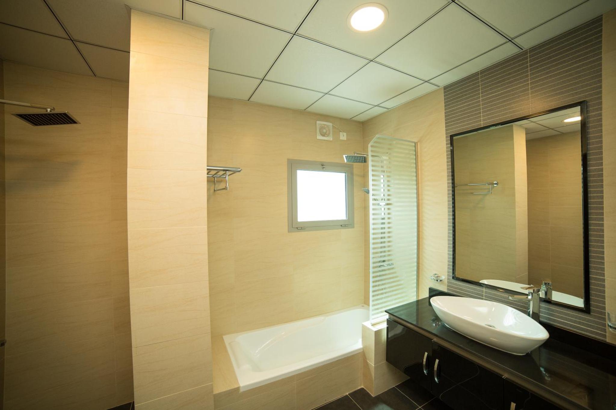 a bathroom with a sink and a tub and a mirror at Golden Rose Luxury Suites (Royal Executive) in Manama