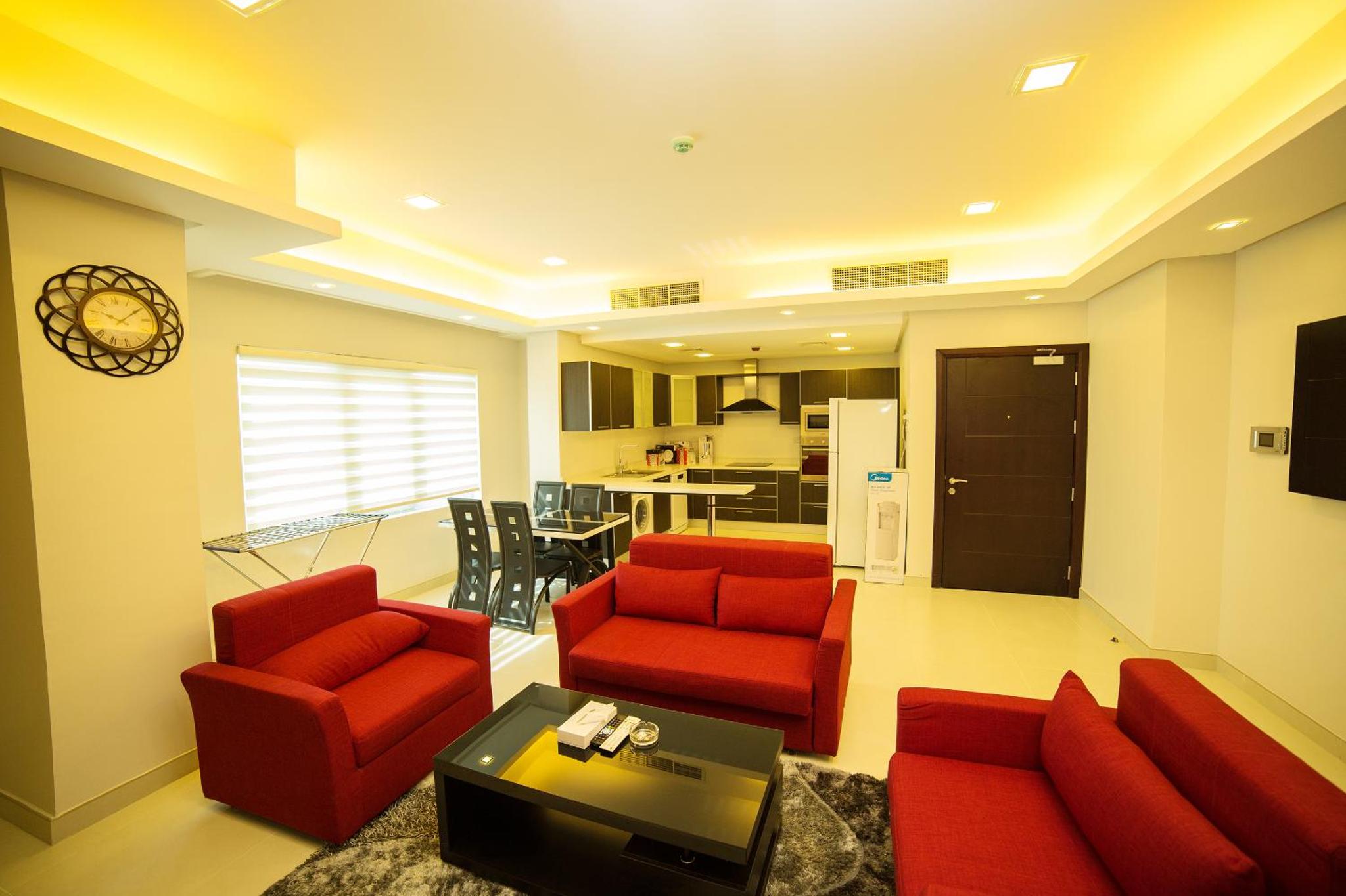 a living room with red furniture and a kitchen at Golden Rose Luxury Suites (Royal Executive) in Manama