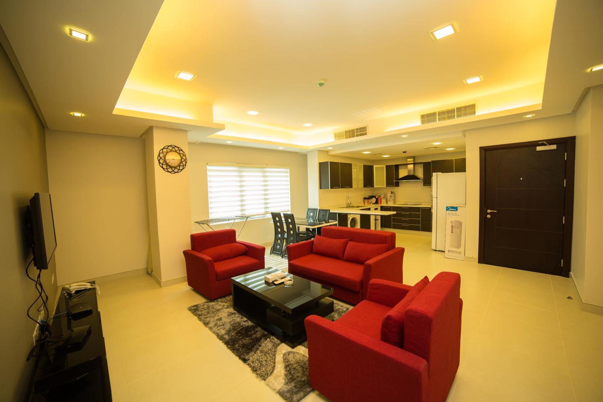 a living room with red chairs and a tv at Golden Rose Luxury Suites (Royal Executive) in Manama