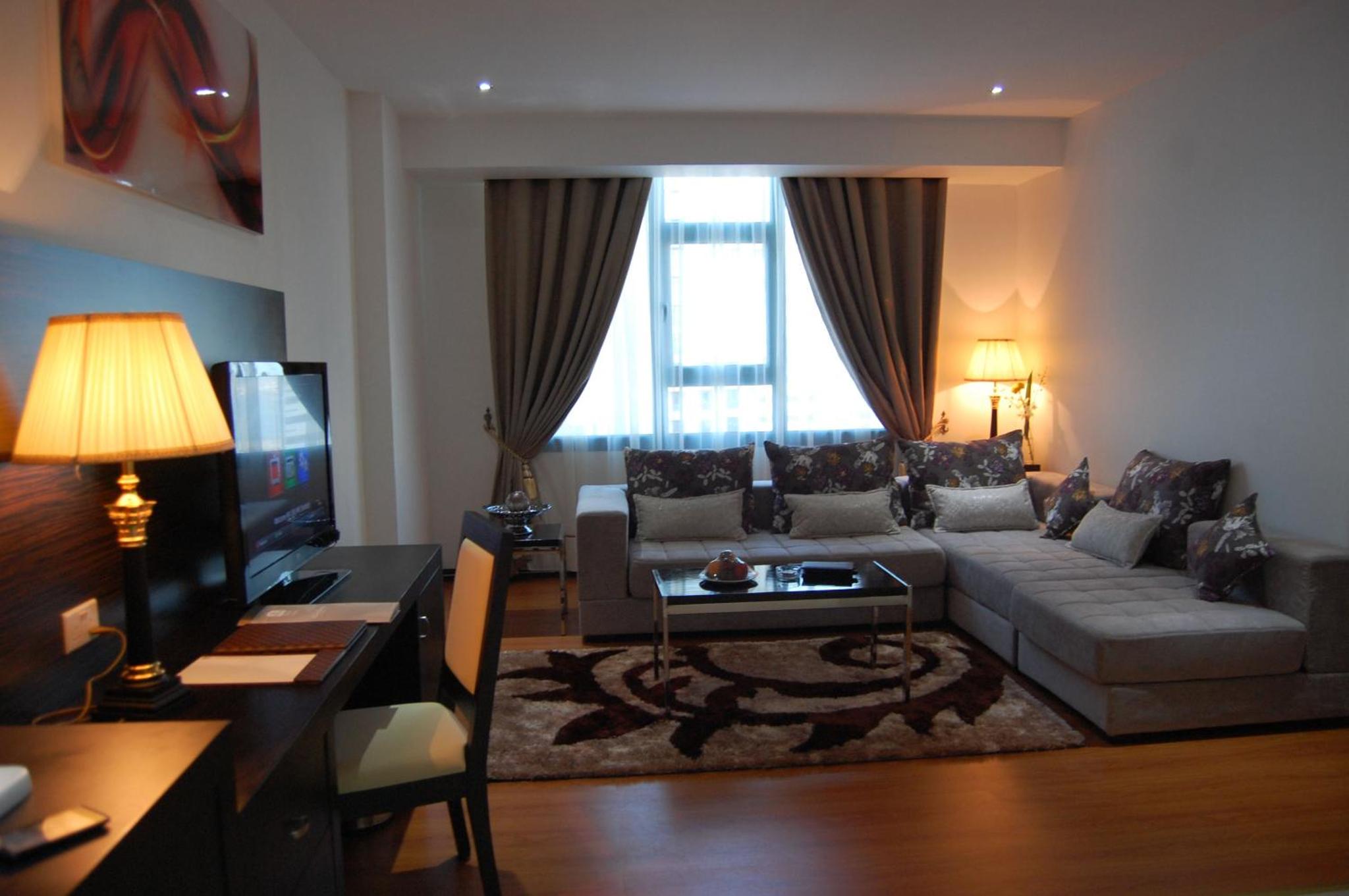 a living room with a couch and a tv at The Olive Hotel, Juffair in Manama