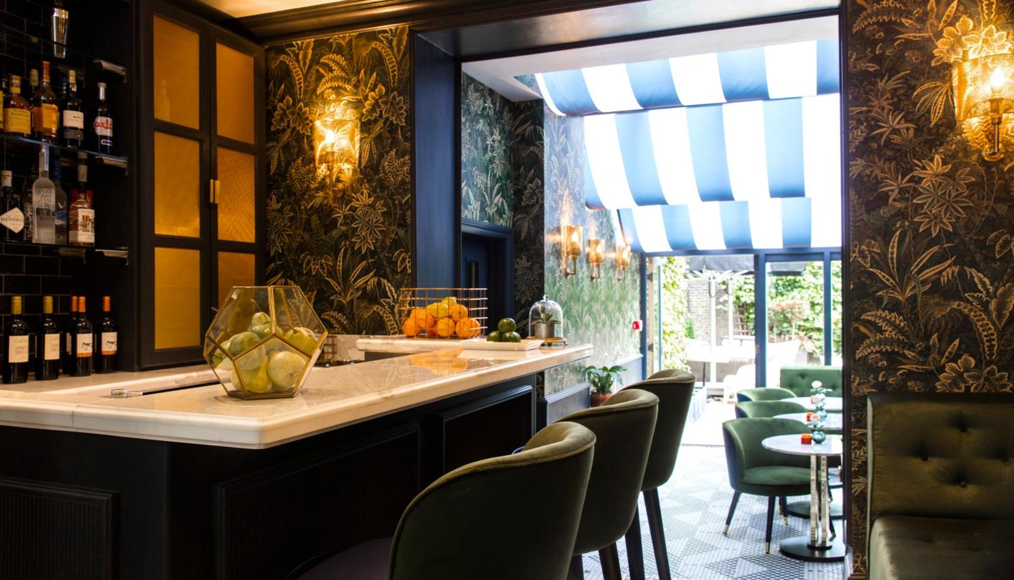 a bar with chairs and a counter with wine bottles at The Academy - Small Luxury Hotels of the World in London