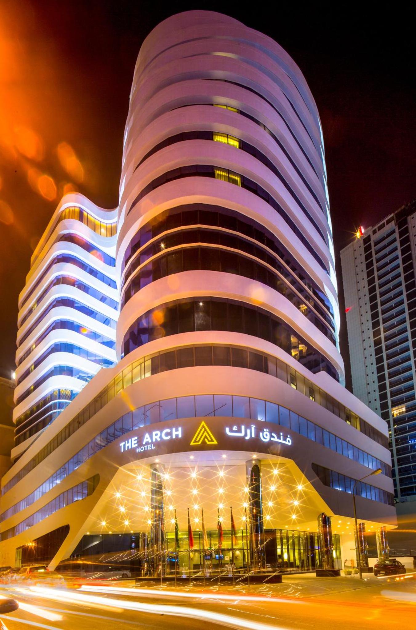 a large building with a sign on it at night at Arch Hotel in Manama