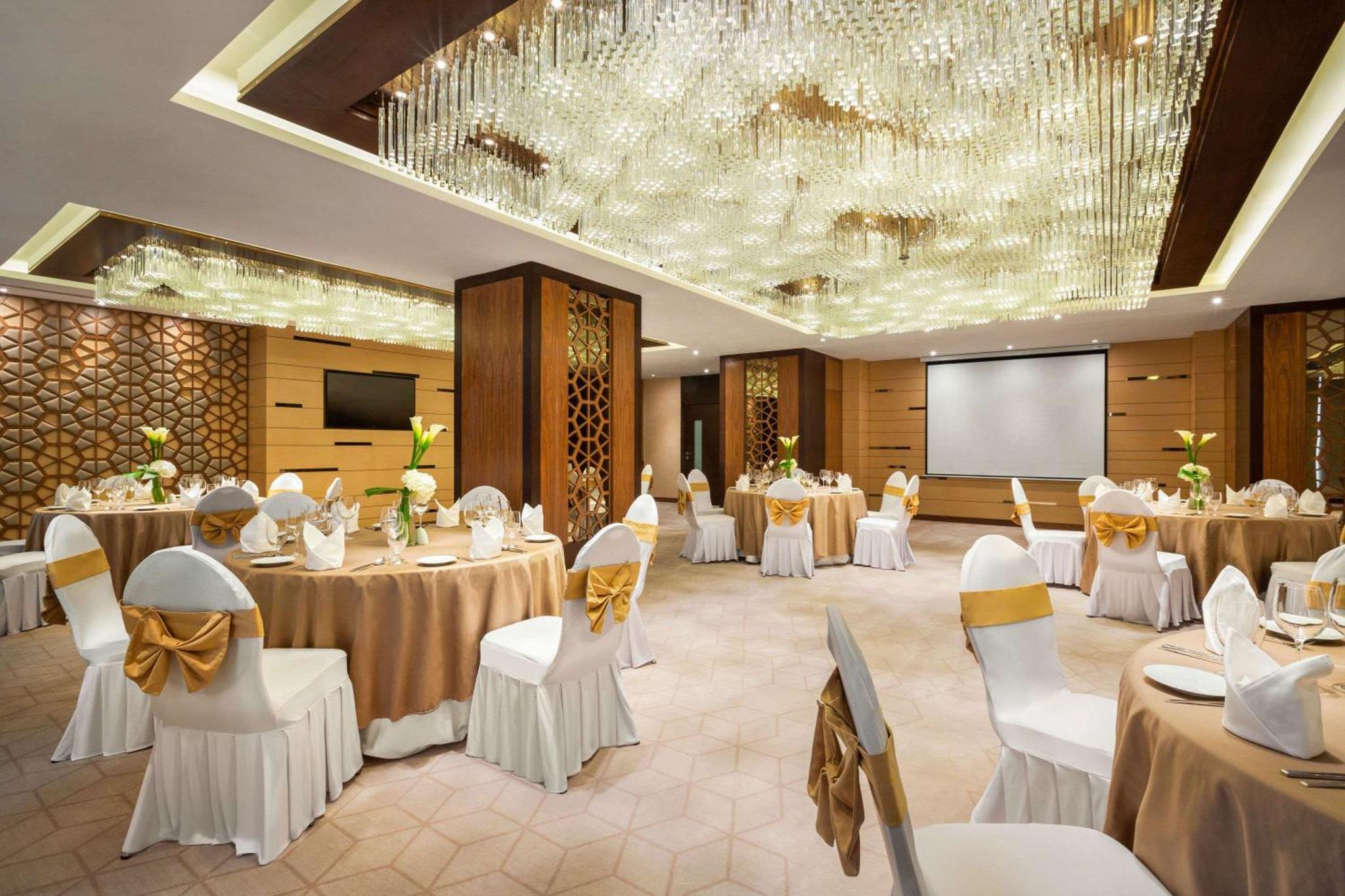 a banquet hall with tables and chairs and a screen at Wyndham Garden Manama in Manama +90 photos