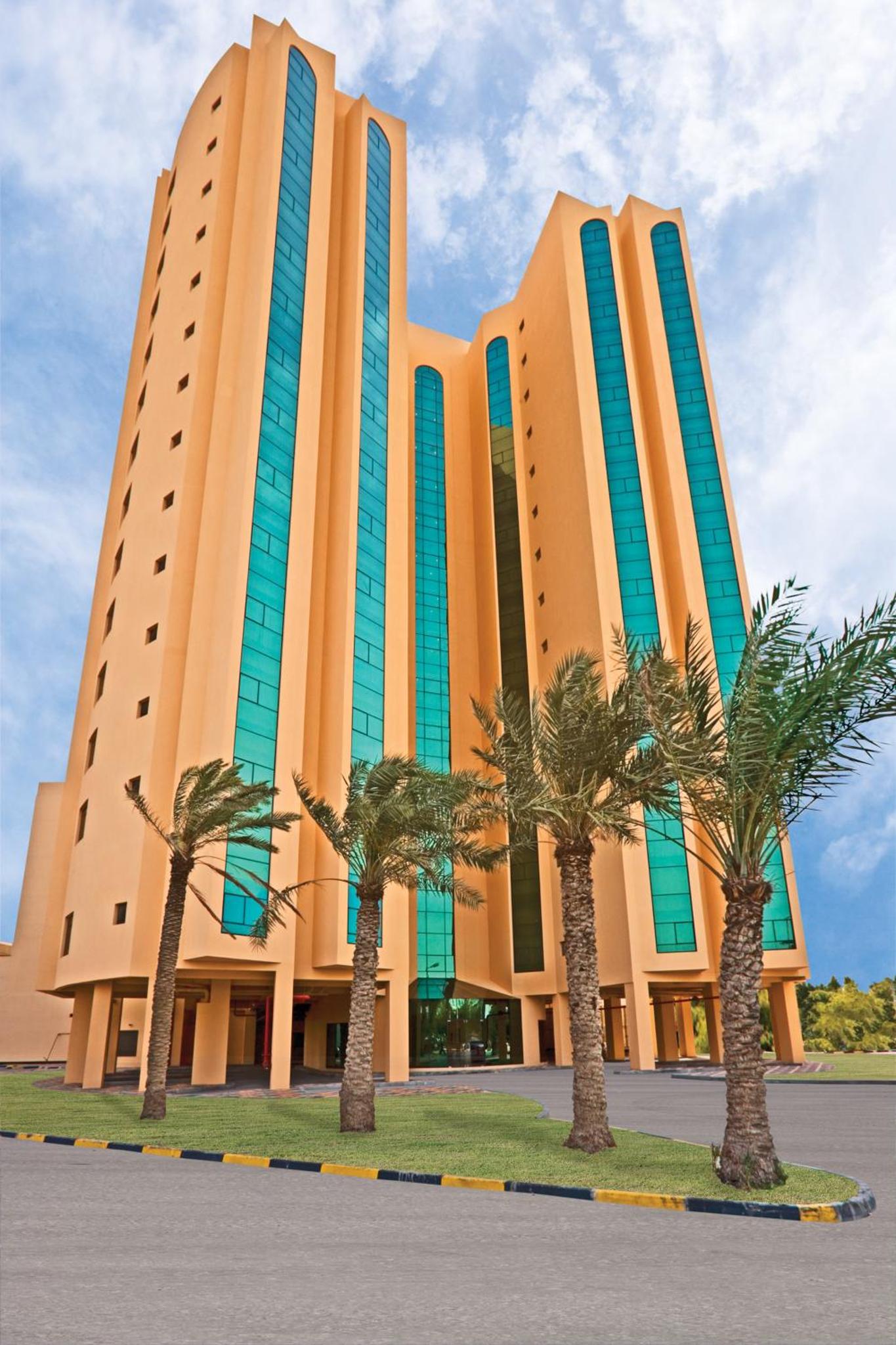 a large building with palm trees in front of it at Gulf Executive Residence in Manama