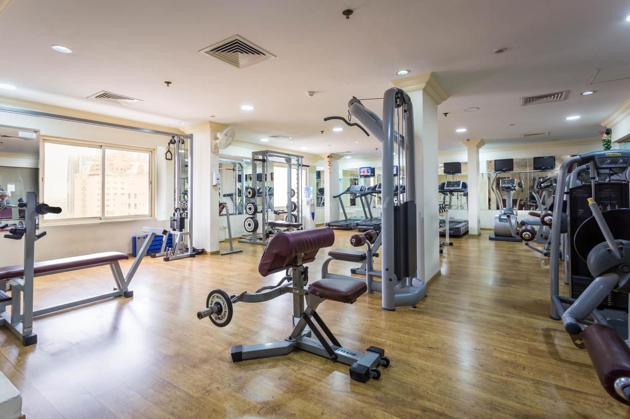 a gym with several treadmills and machines in a room at Al Safir Tower - Residence in Juffair