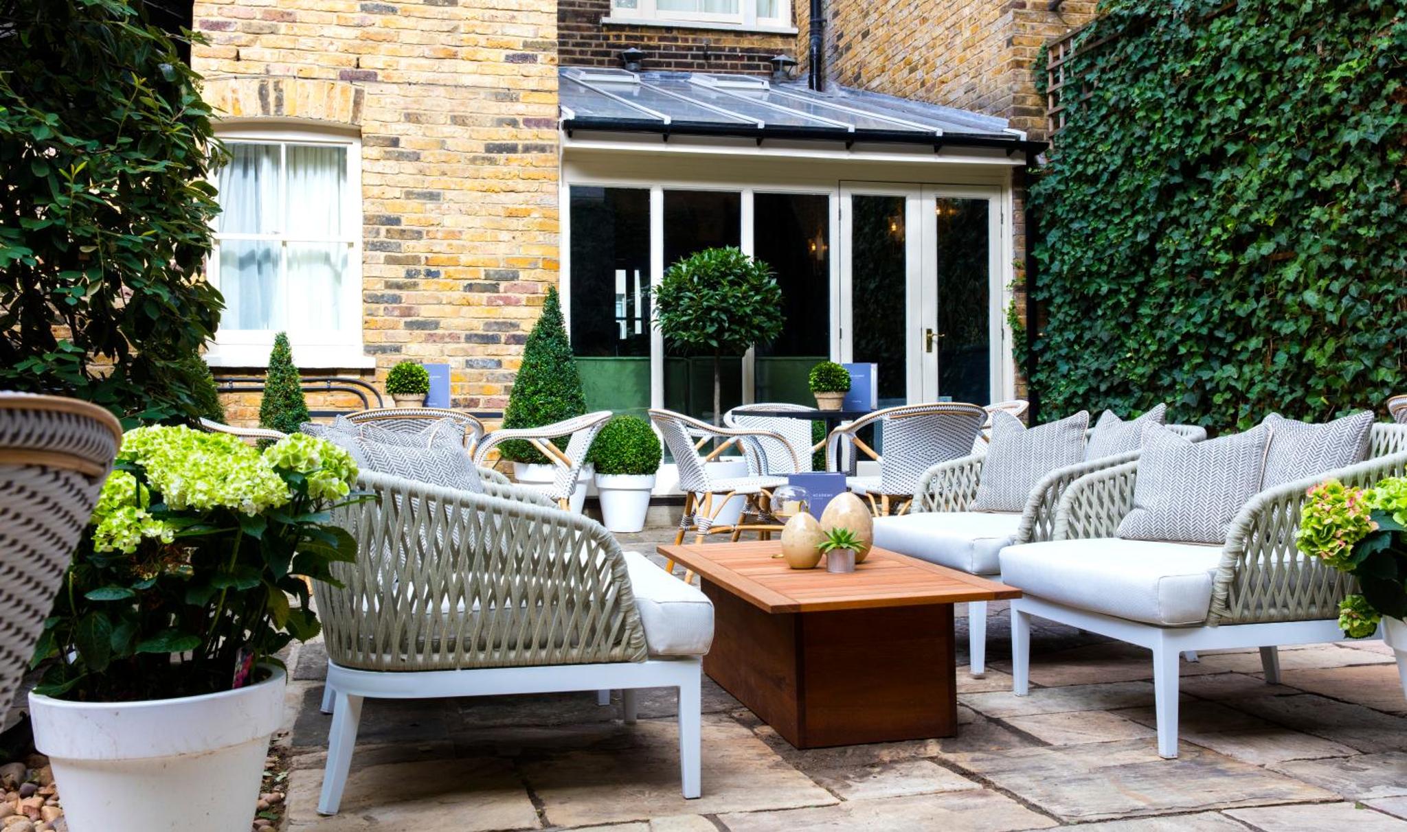 a group of chairs and tables on a patio at The Academy - Small Luxury Hotels of the World in London