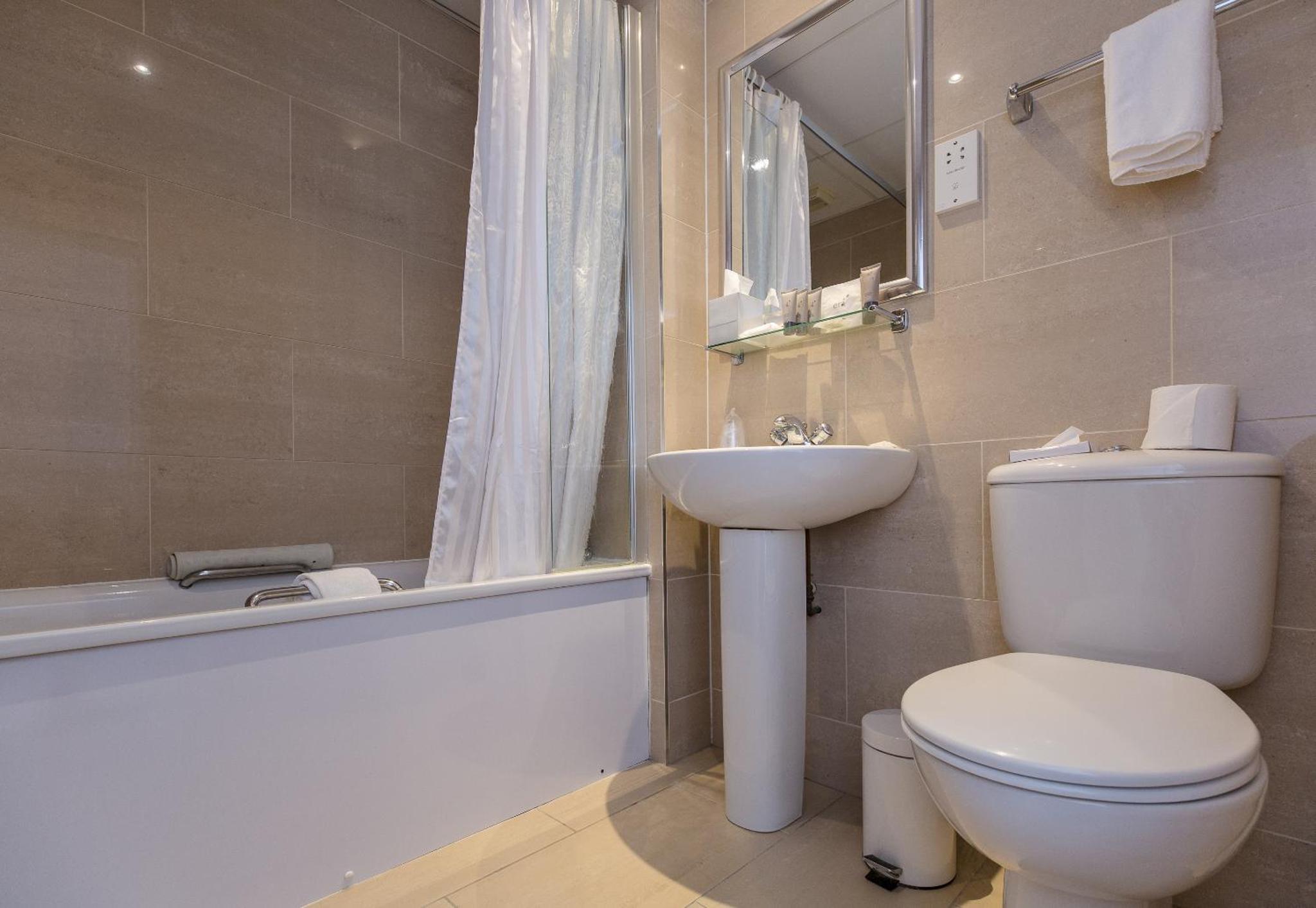 a bathroom with a toilet and a sink and a bath tub at Phoenix Hotel in London