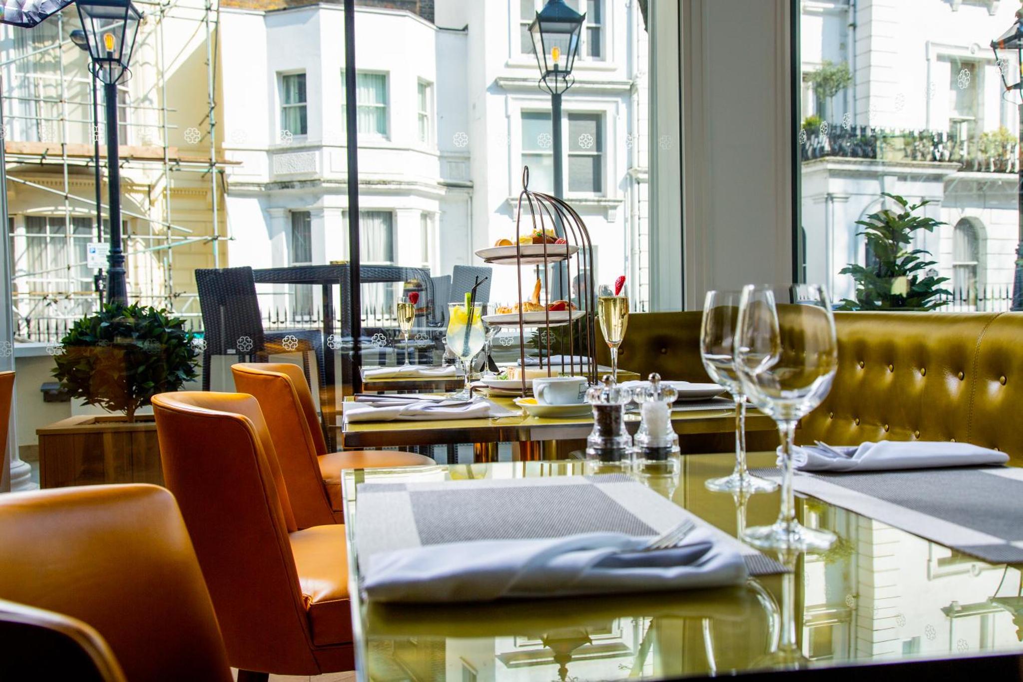 a restaurant with a table and chairs and a window at Blakemore Hyde Park in London