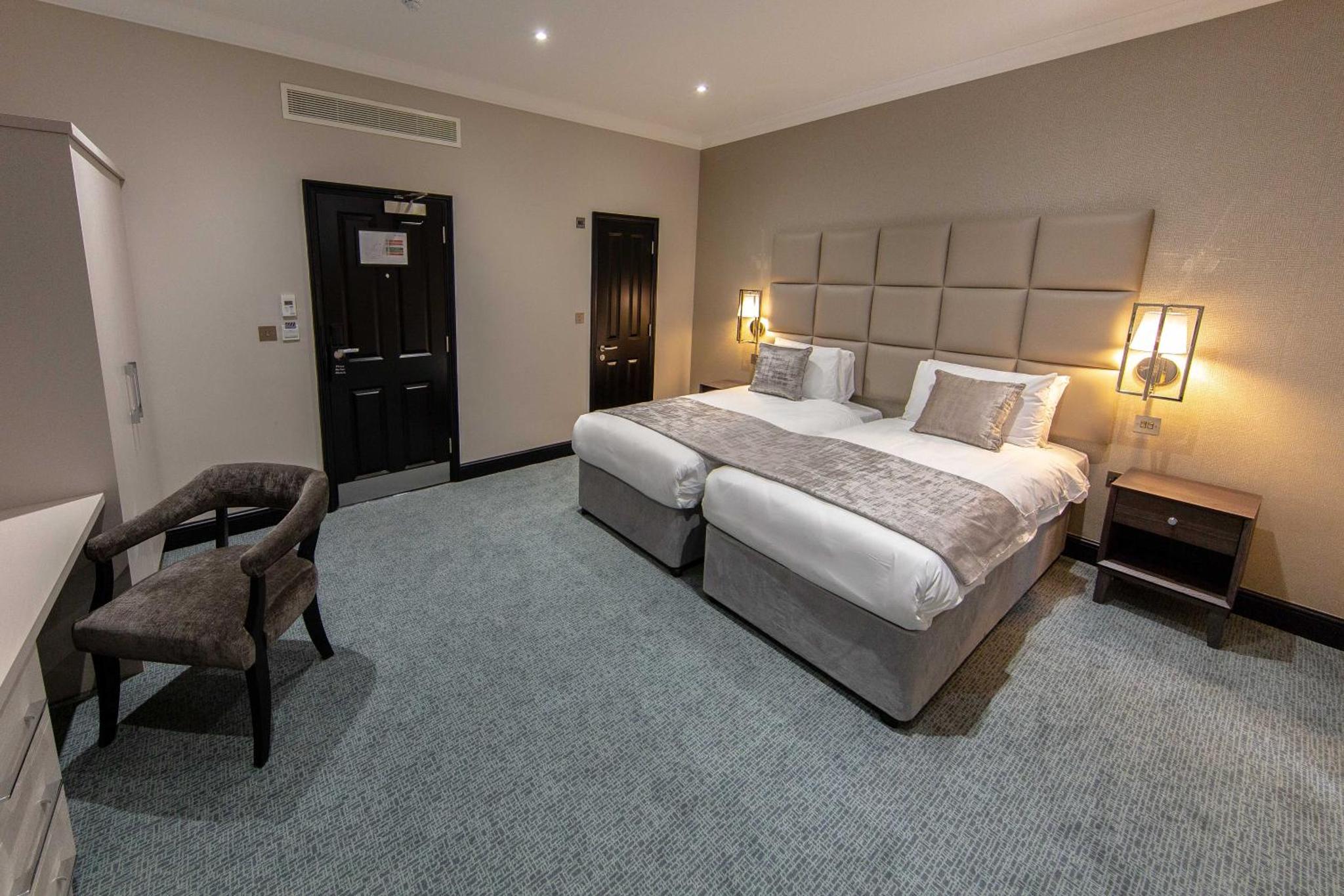 a hotel room with a large bed and a chair at The Crescent Hyde Park in London