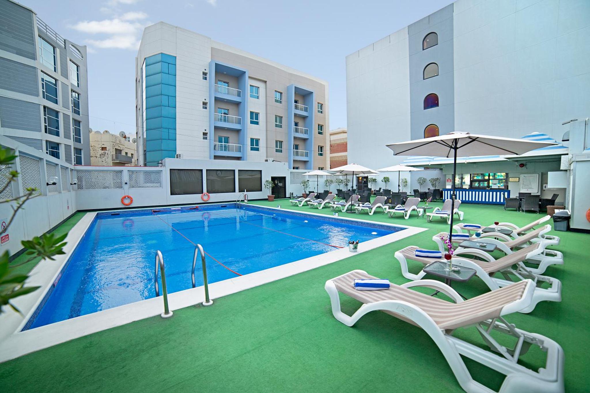 a swimming pool with lounge chairs and umbrellas at Ramada by Wyndham Bahrain in Manama