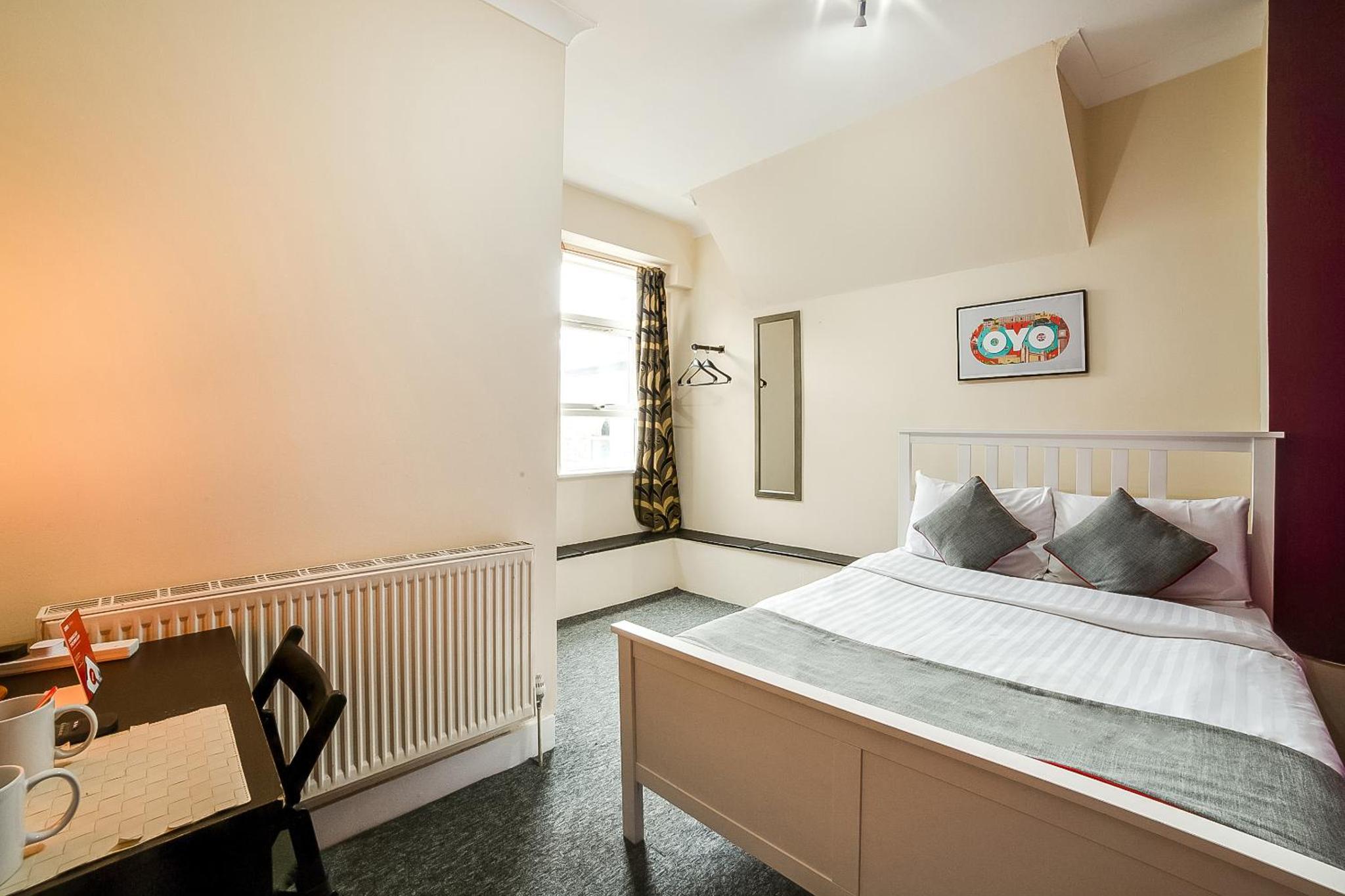 a bedroom with a bed and a desk and a window at Stratford Hotel in London