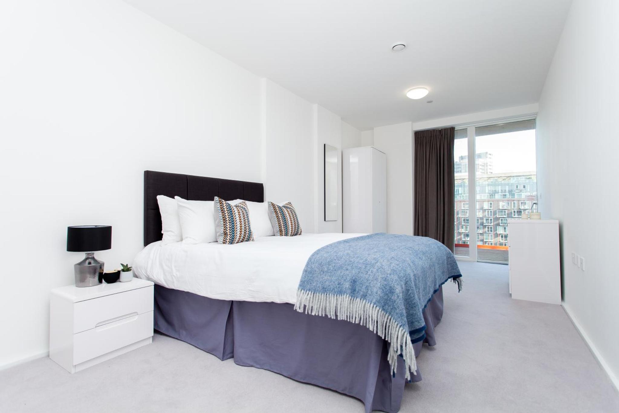 a white bedroom with a large bed and a window at Clover Court by Aeria Apartments in London