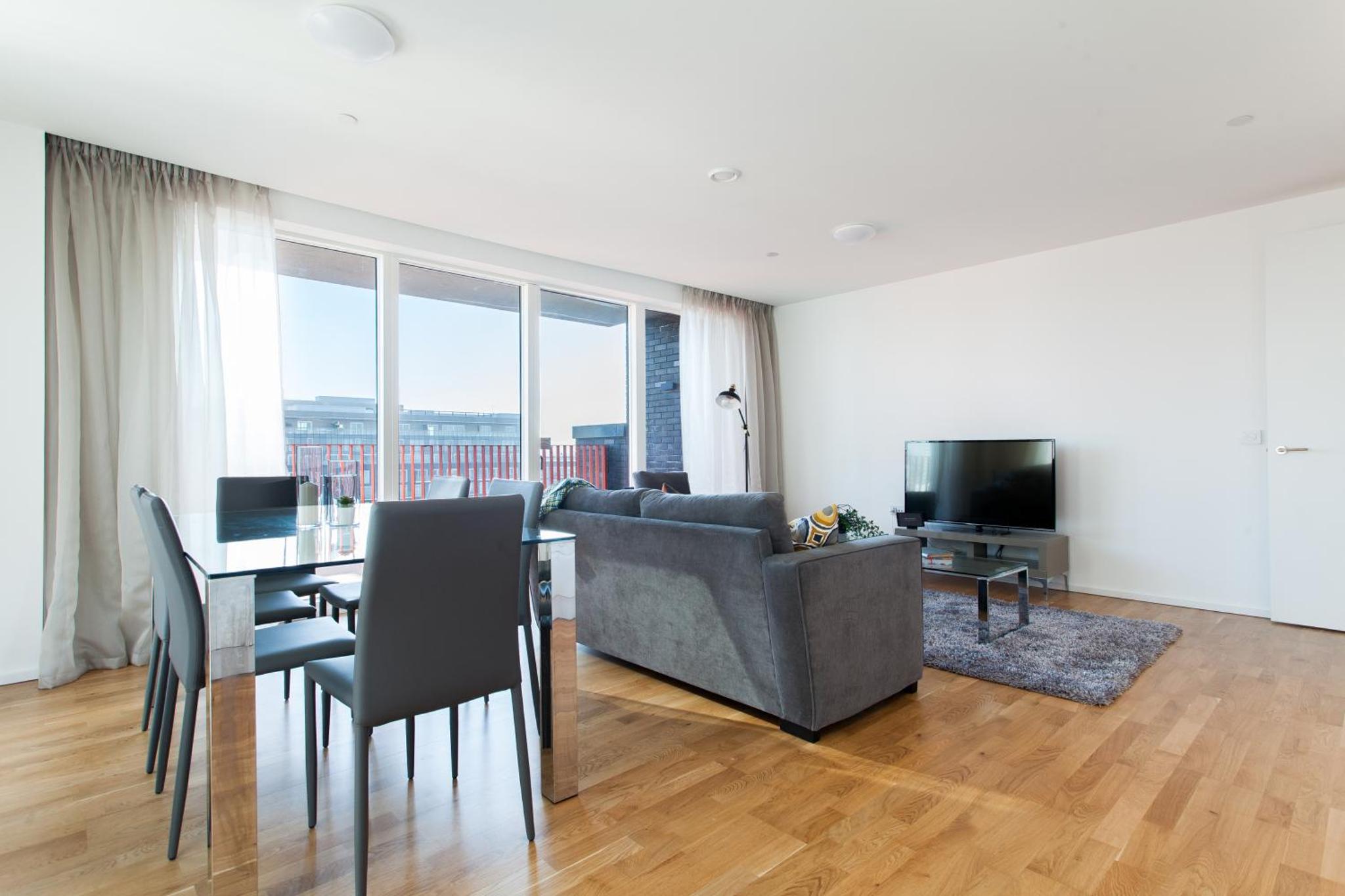 a living room with a couch and a table with chairs at Clover Court by Aeria Apartments in London