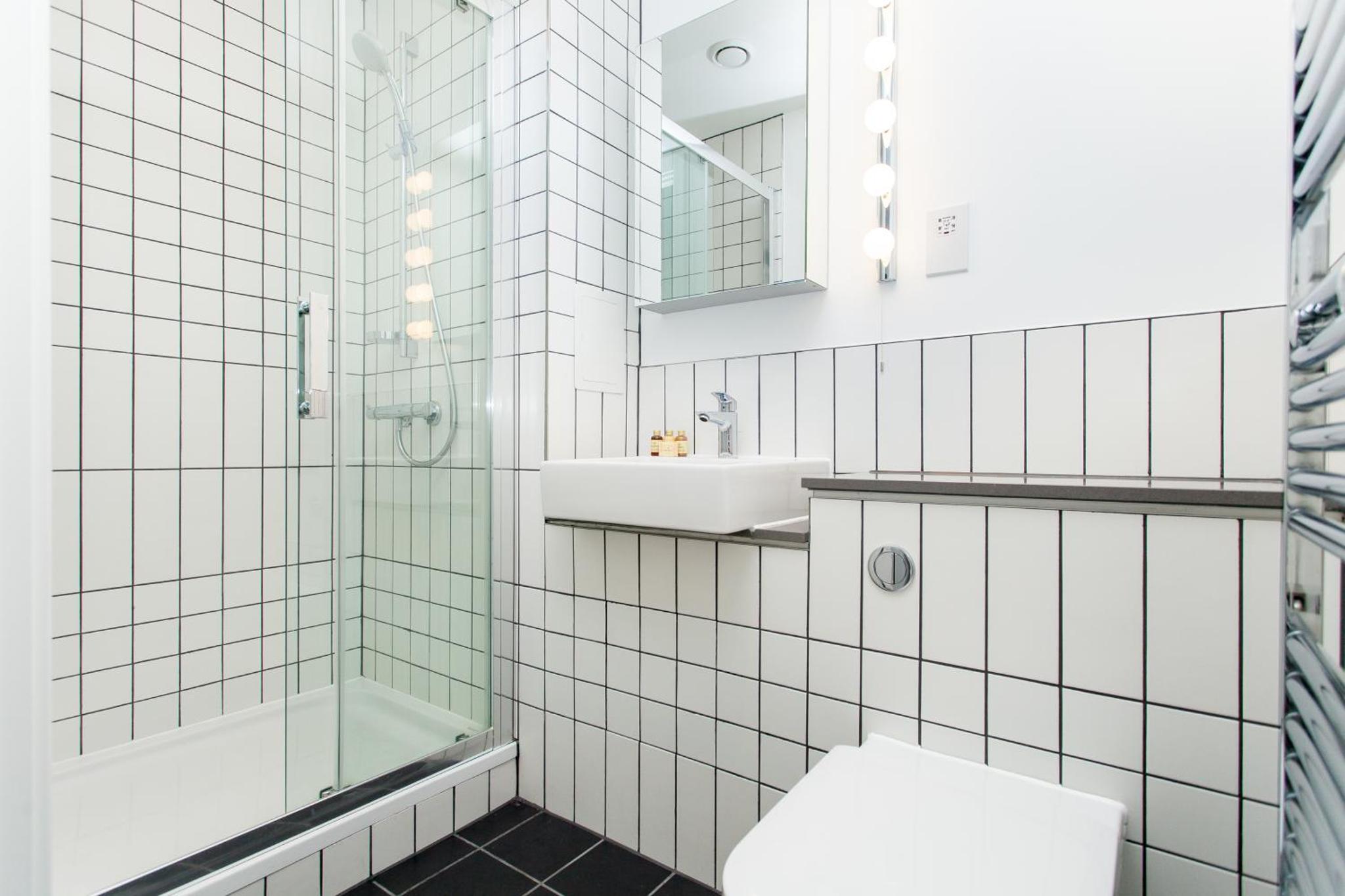 a bathroom with a shower and a toilet and a sink at Clover Court by Aeria Apartments in London +44 photos
