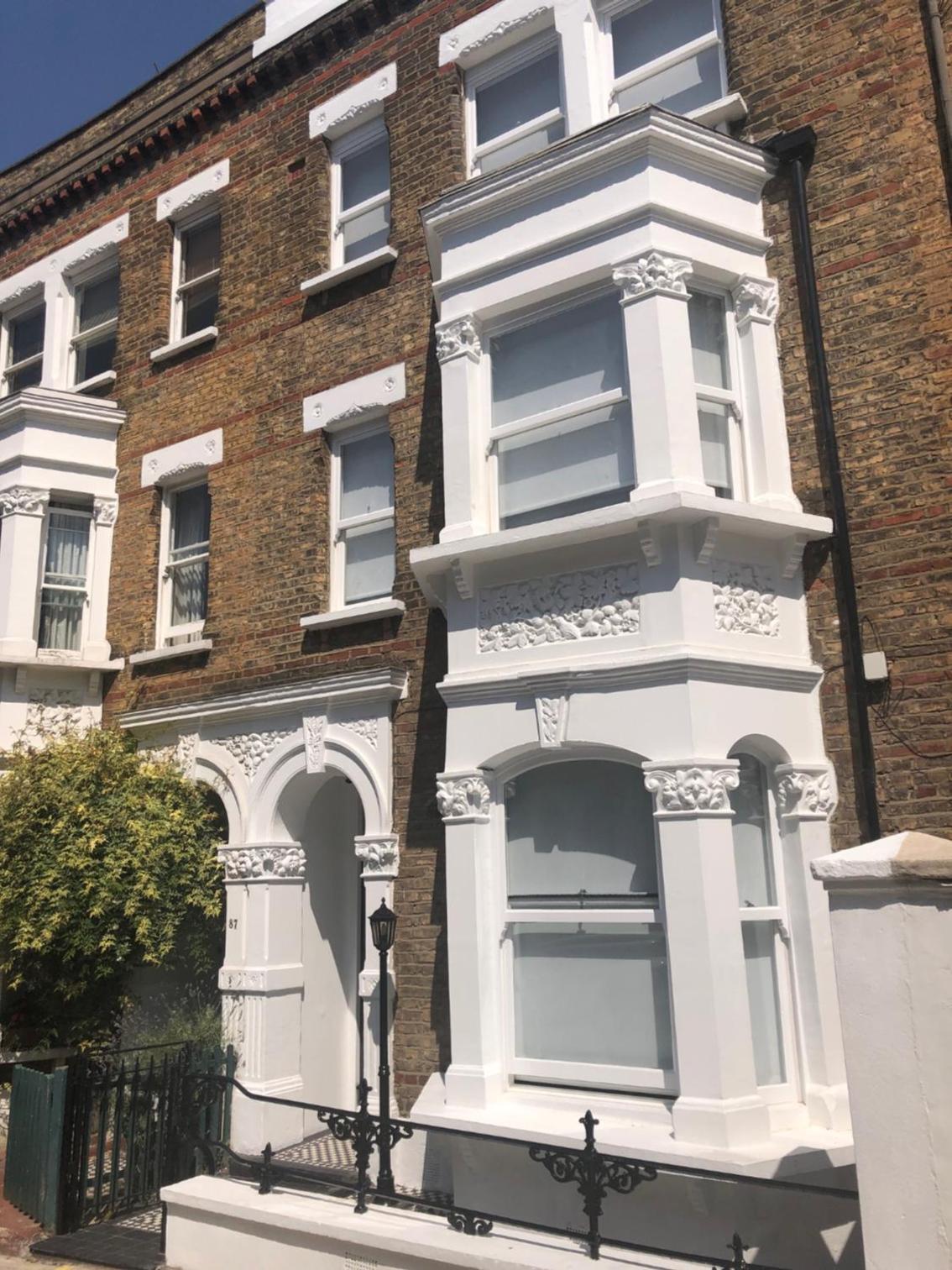 a white house with white trim in front of a brick building at Messina Studios in London