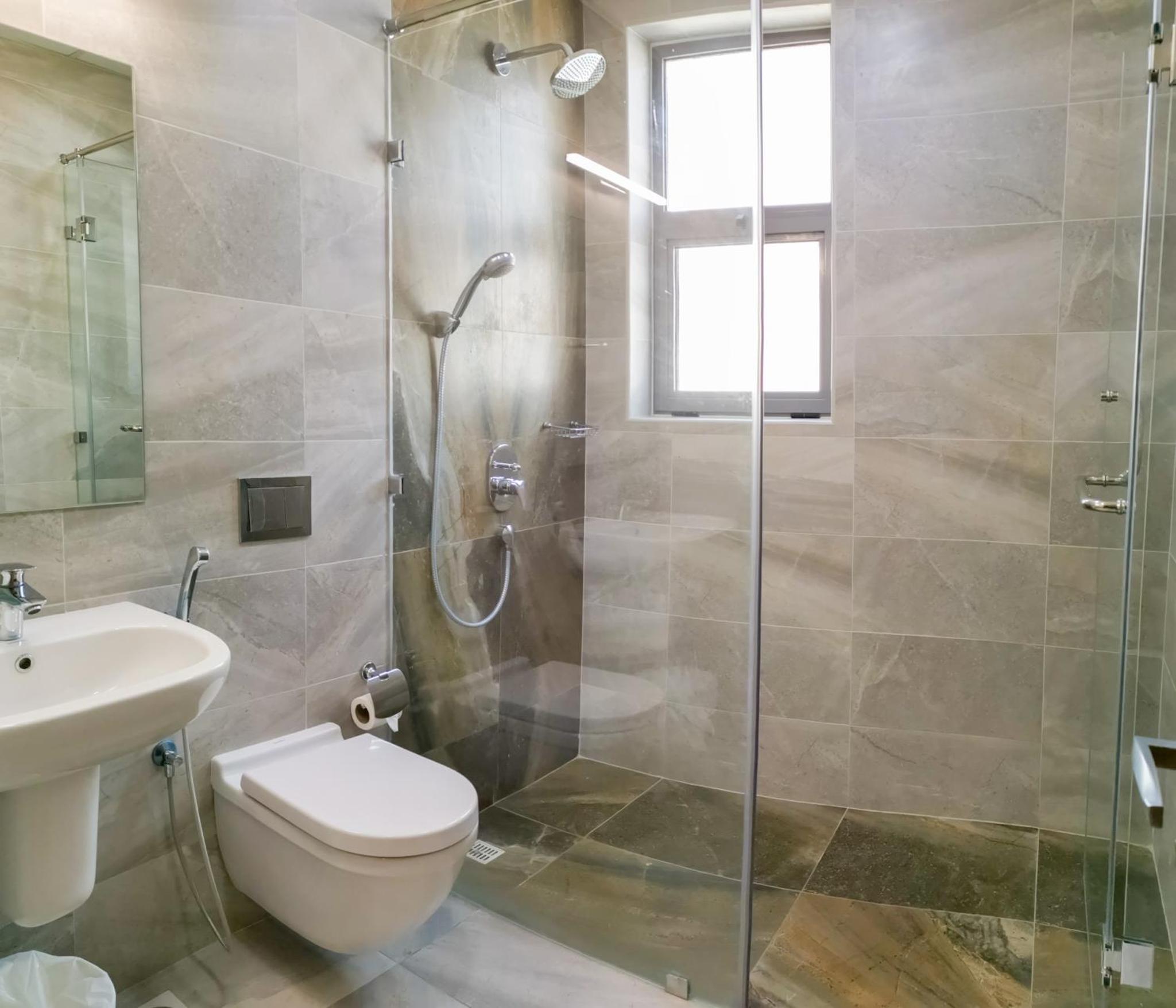 a bathroom with a shower and a toilet and a sink at The Spot Residence in Juffair