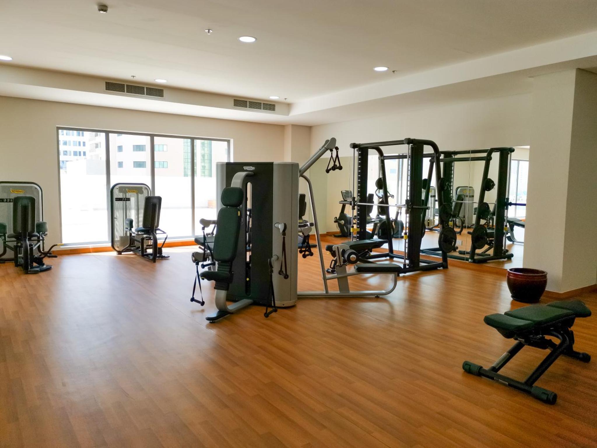 a gym with treadmills and machines in a room at The Spot Residence in Juffair