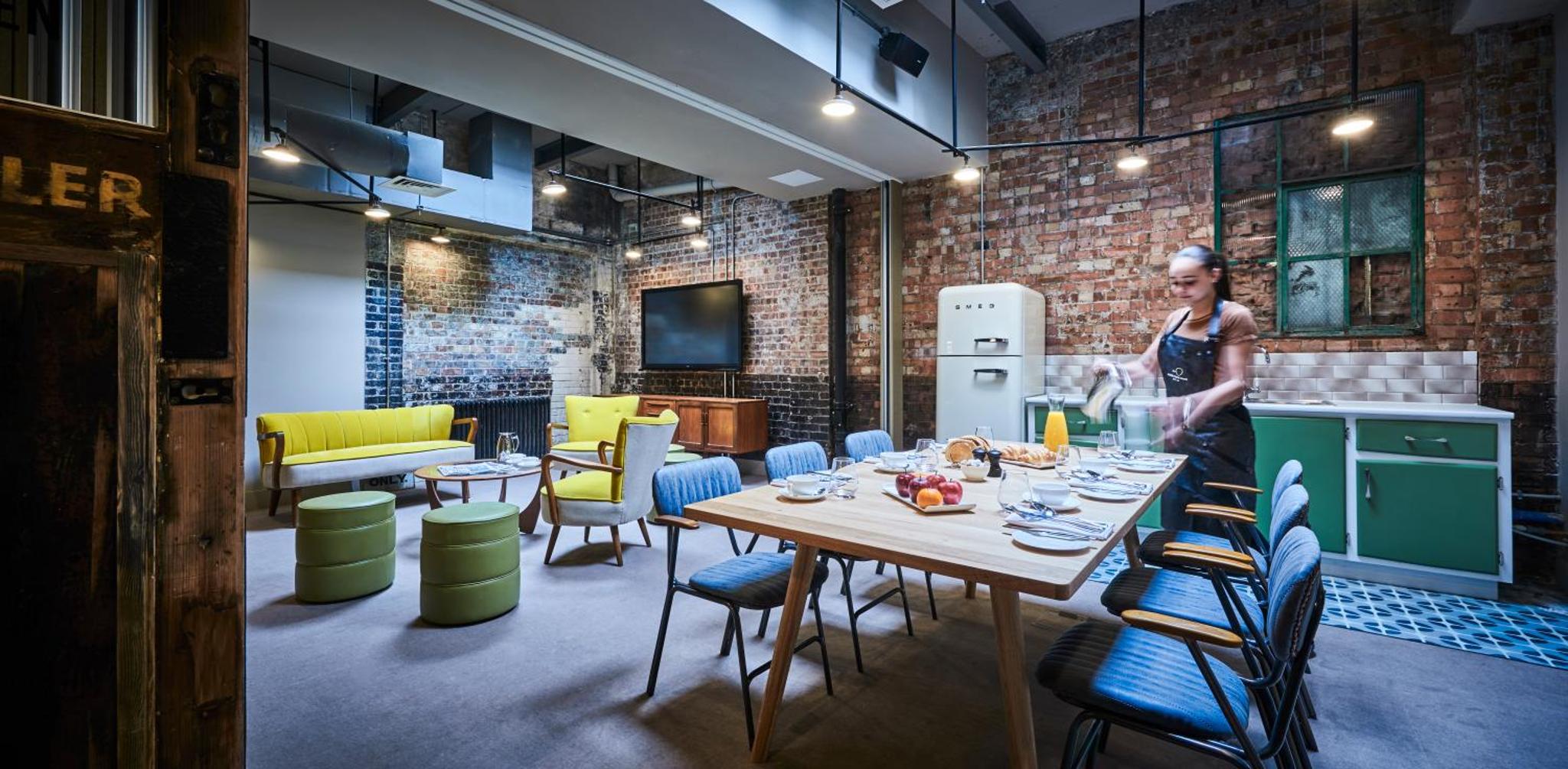 a woman in a kitchen with a table and chairs at New Road Hotel in London