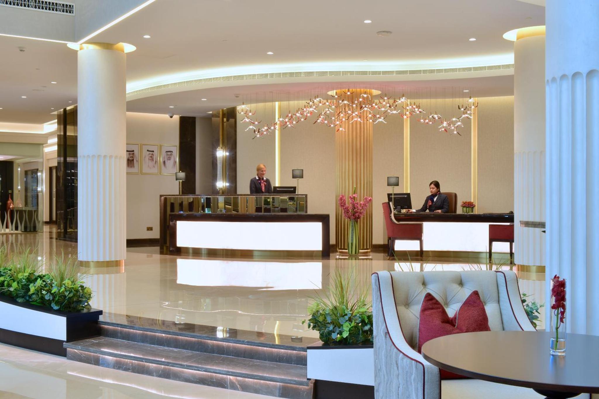 a lobby of a hotel with two people sitting at a desk at Mövenpick Hotel Bahrain in Manama +182 photos