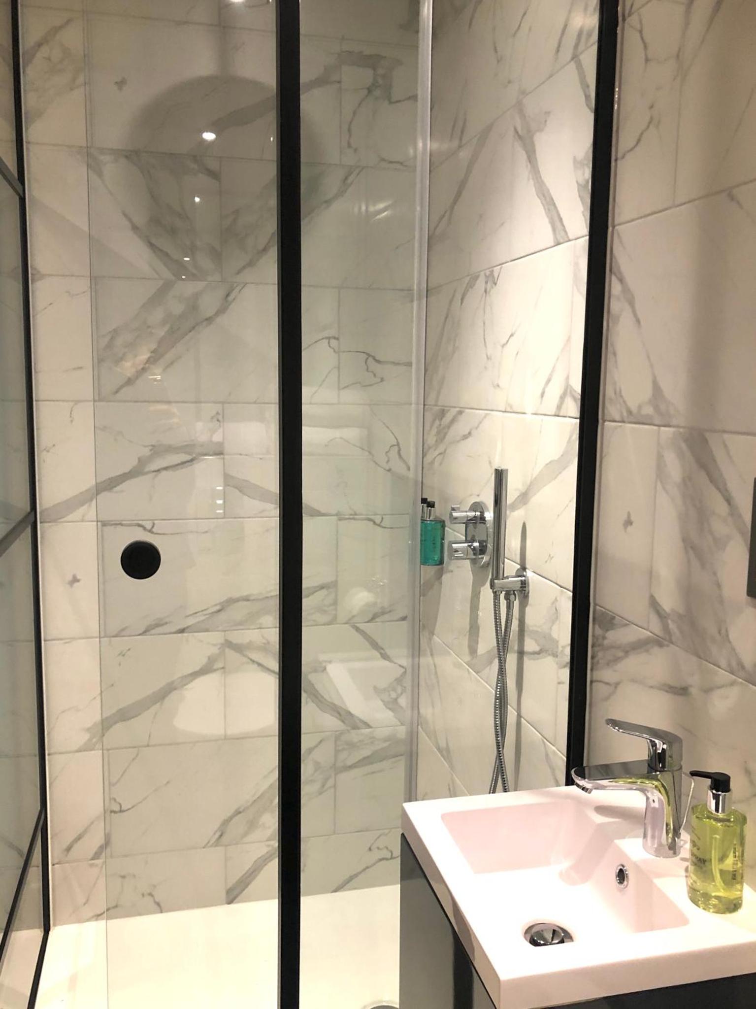 a white bathroom with a shower and a sink at Euston Square Hotel in London +19 photos