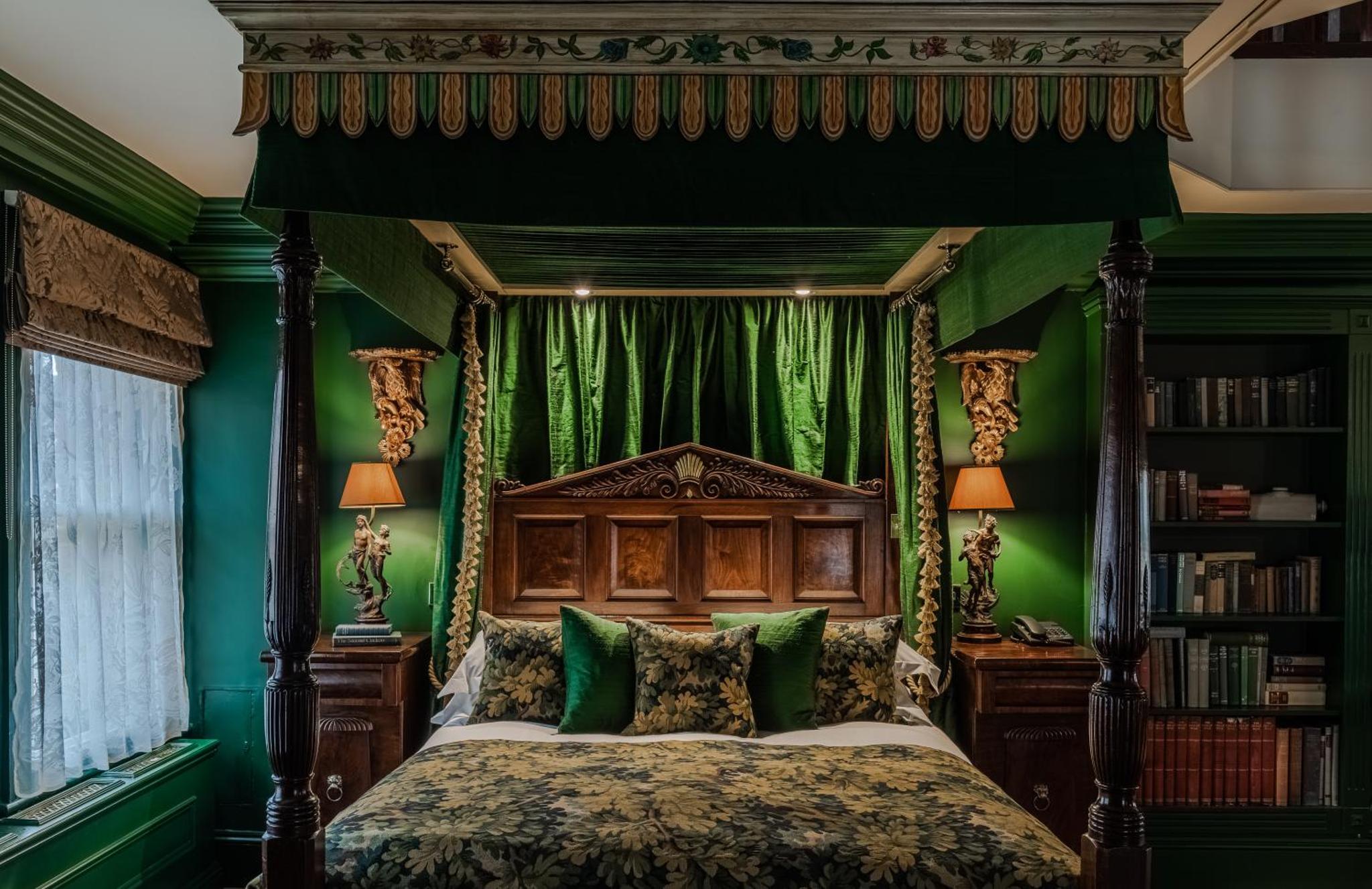 a bedroom with a canopy bed with green walls at The Rookery in London