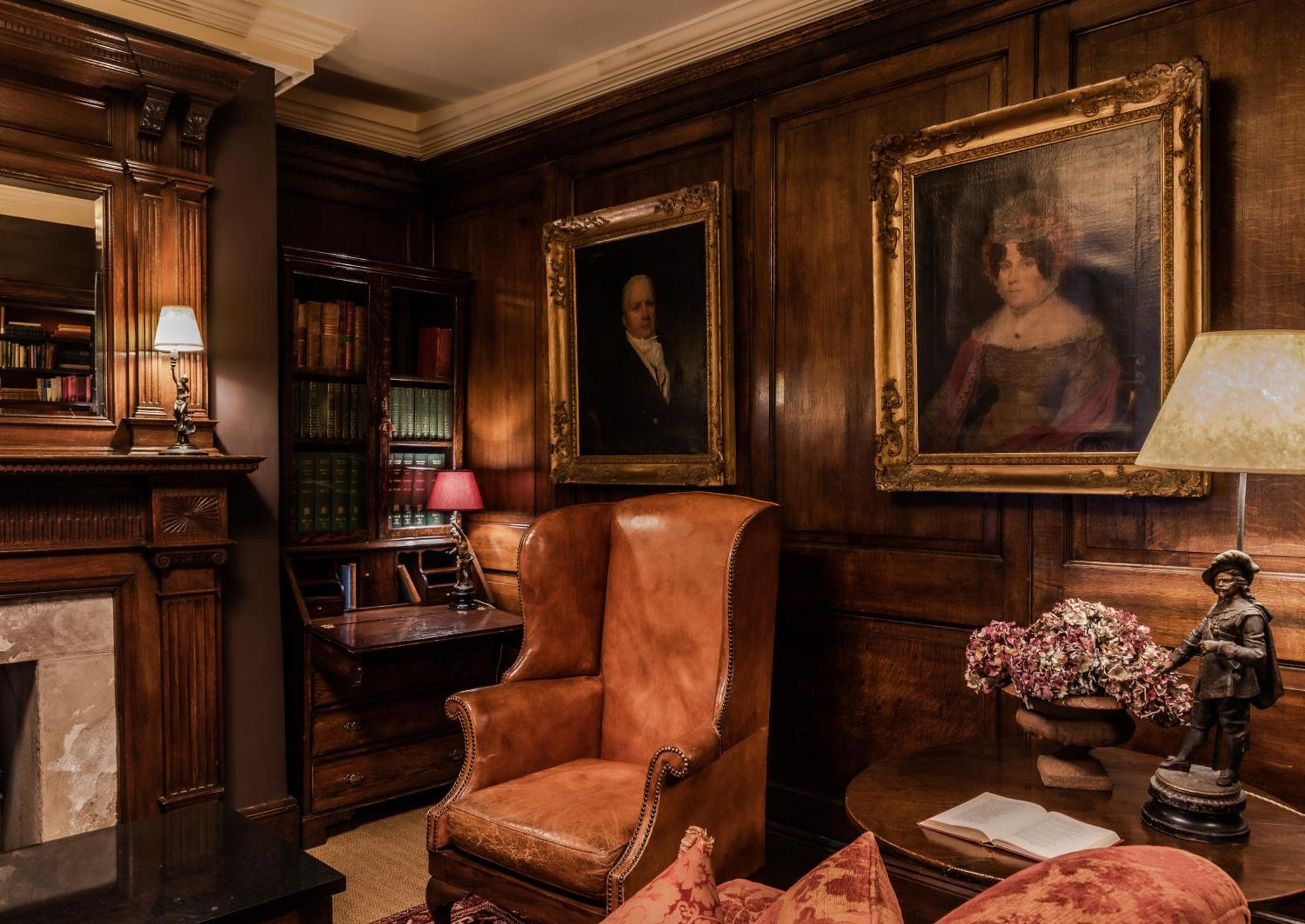 a living room with a chair and a portrait of a woman at The Rookery in London