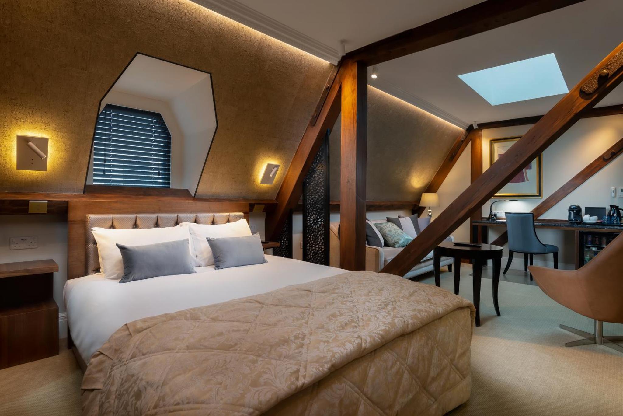 a bedroom with a large bed and a staircase at The Lansbury Heritage Hotel and Spa By Sunday - Canary Wharf London in London