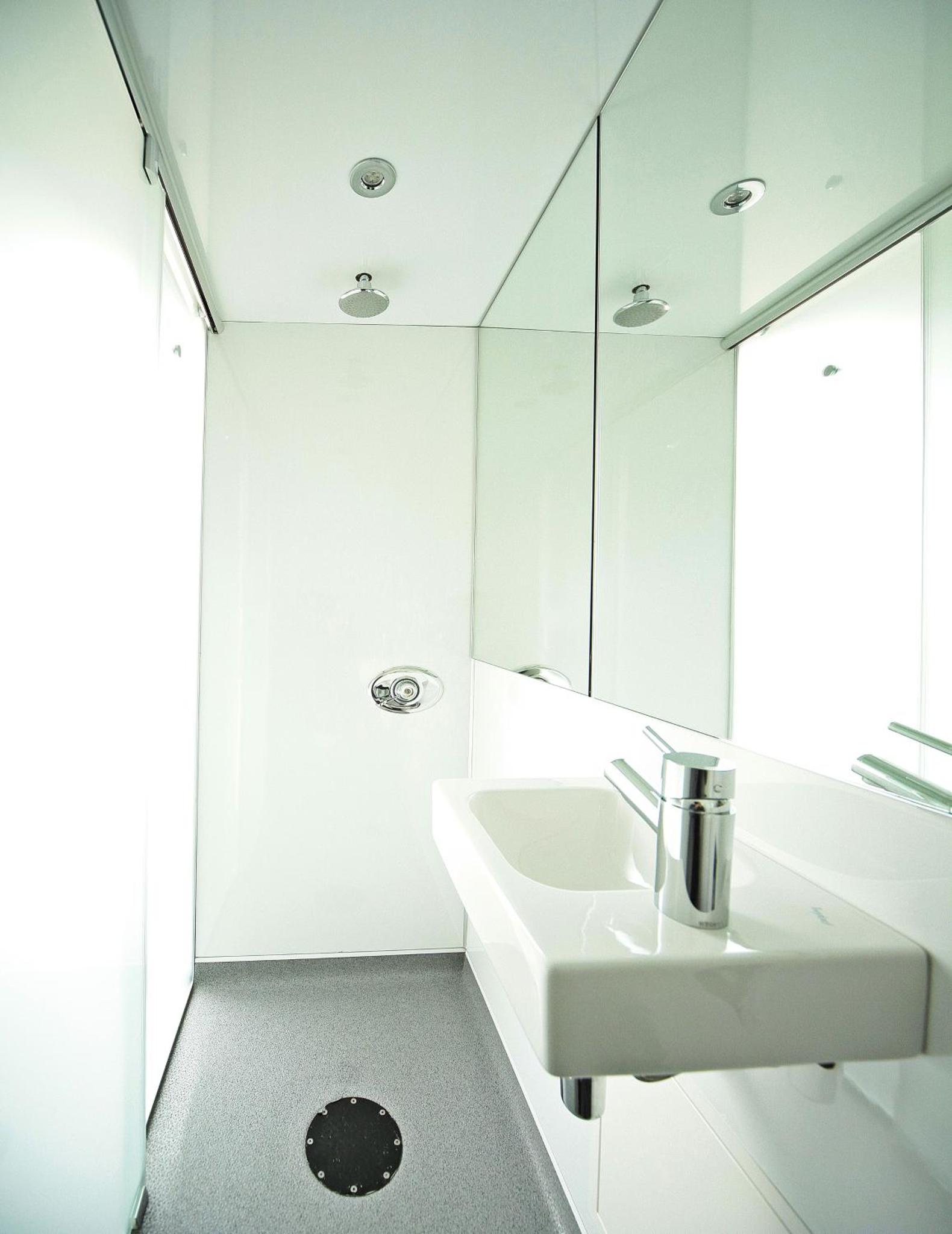 a white bathroom with a sink and a mirror at Snoozebox Olympic Park in London