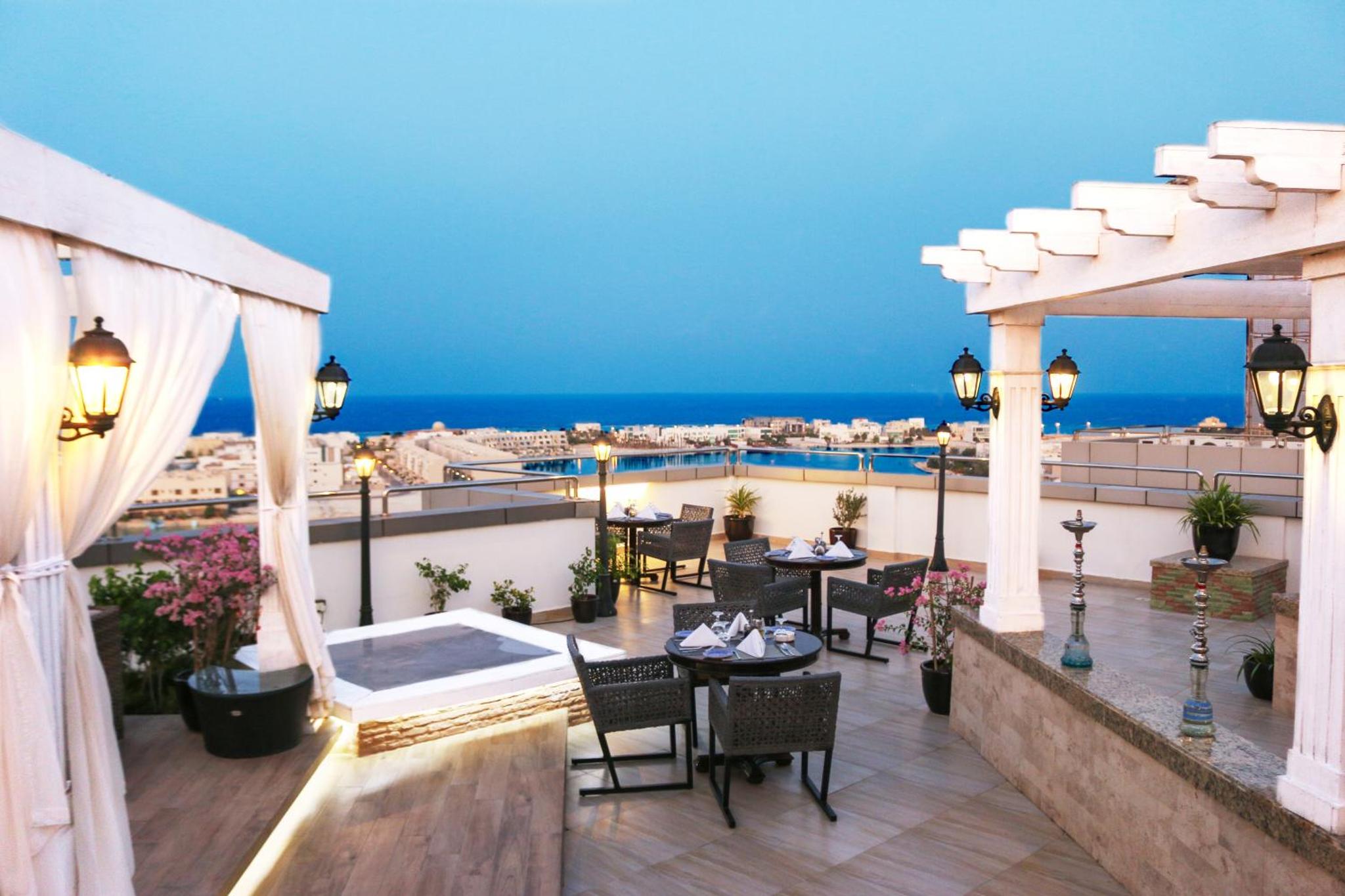 a balcony with tables and chairs and a view of the ocean at Ramada Hotel and Suites Amwaj Islands in Manama