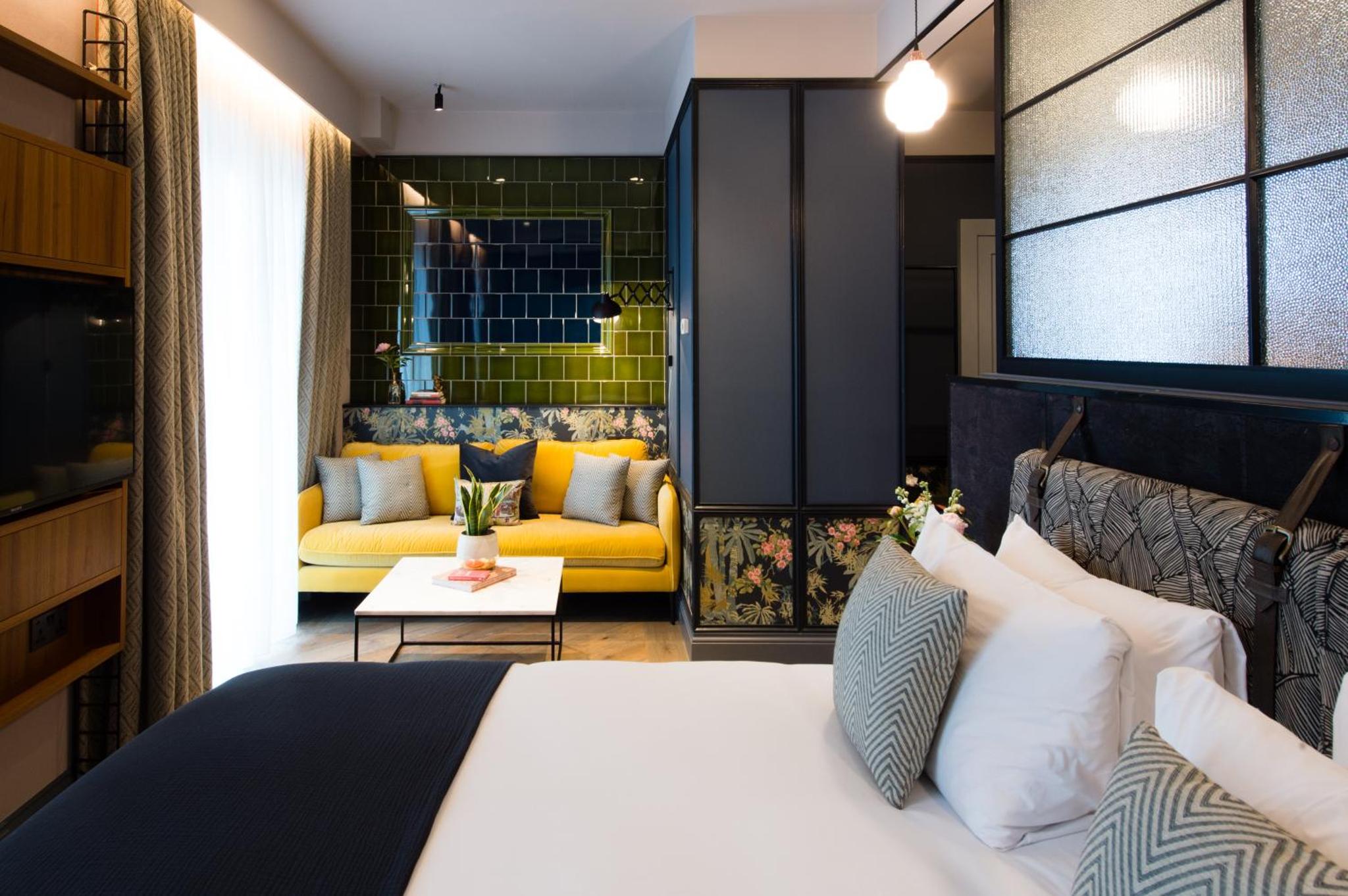 a hotel room with a bed and a yellow couch at Clayton Hotel City of London, Tower Bridge in London