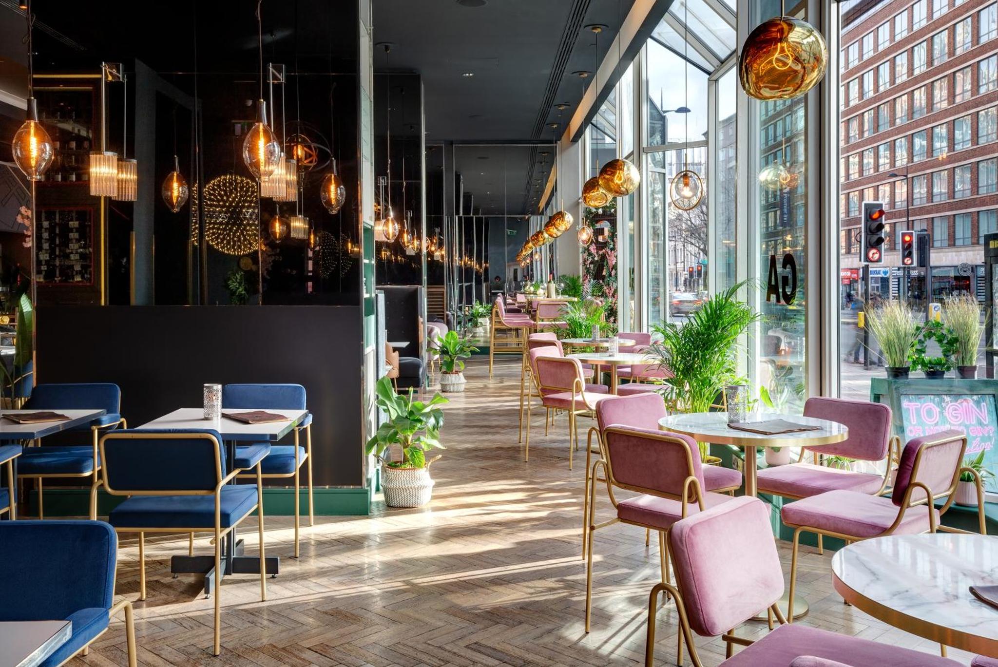 a restaurant with tables and chairs and windows at Pullman London St Pancras in London