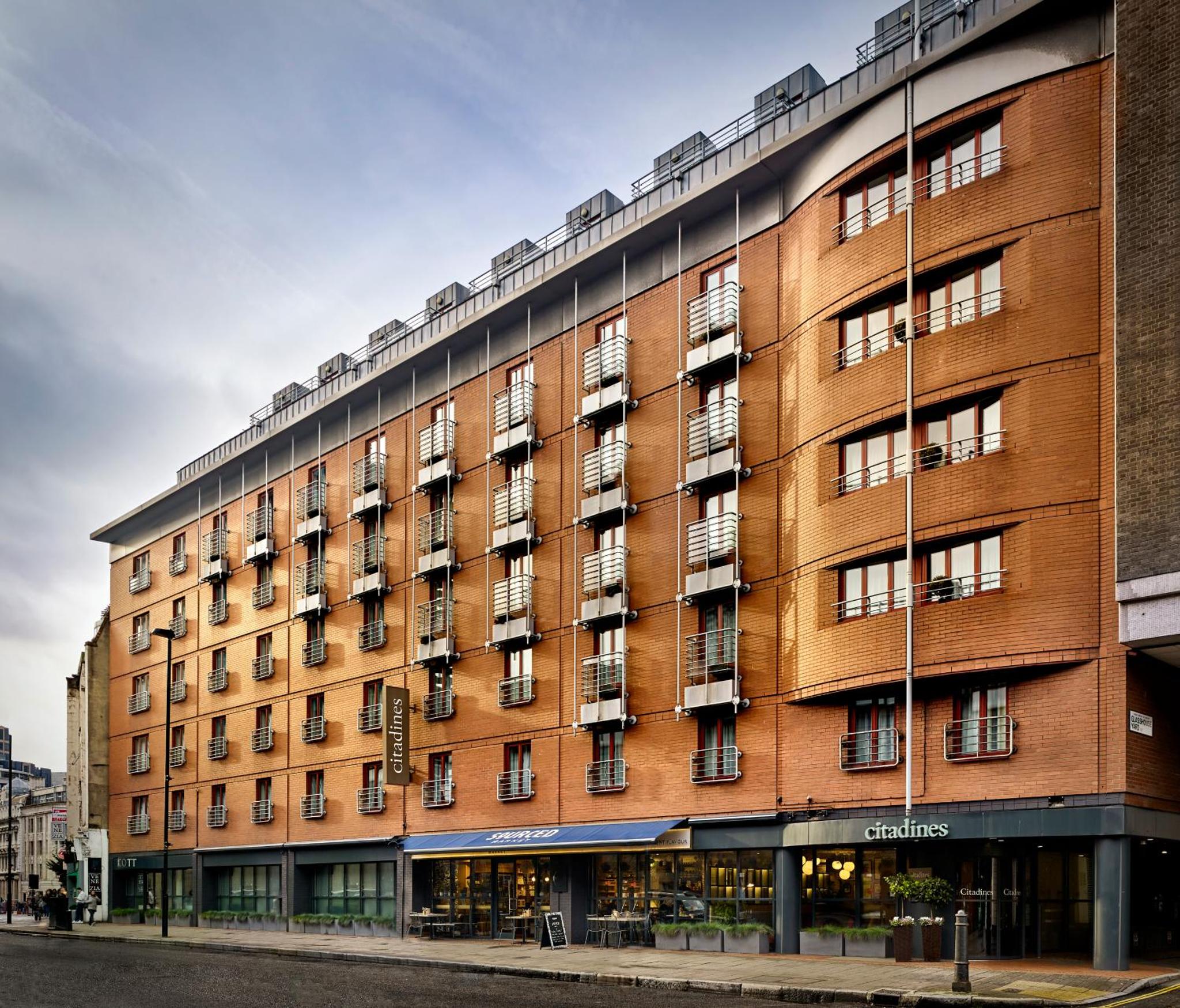a large brick building on a city street at Citadines Barbican London in London