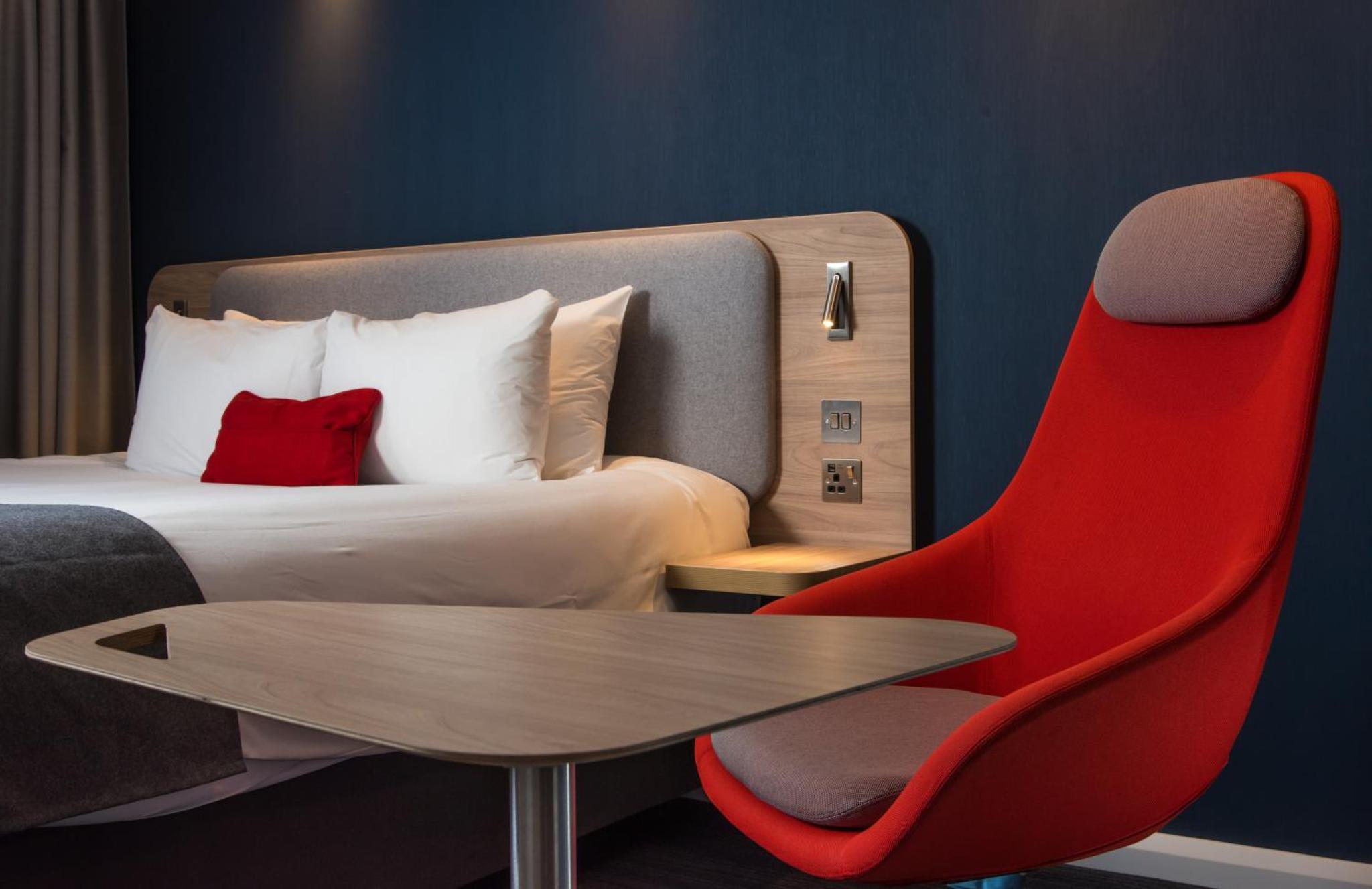 a hotel room with a bed and a red chair at Holiday Inn Express London-Hammersmith by IHG in London +17 photos