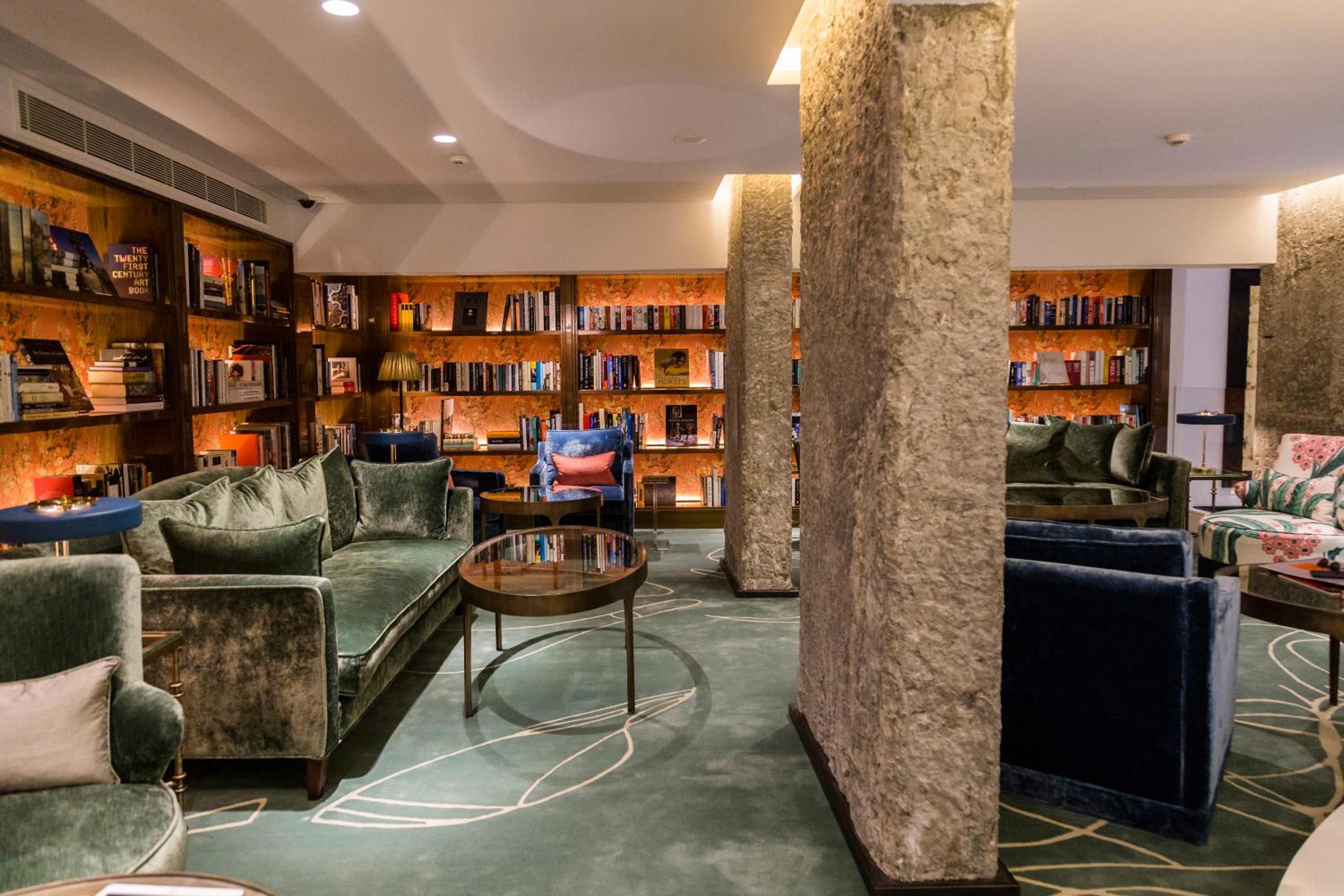 a library with couches and tables and bookshelves at The Merchant House in Manama