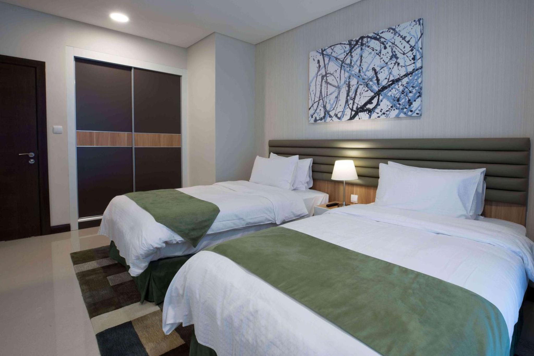 a bedroom with two beds and a painting on the wall at Gulf Executive Hotel & Residence Juffair in Manama +62 photos
