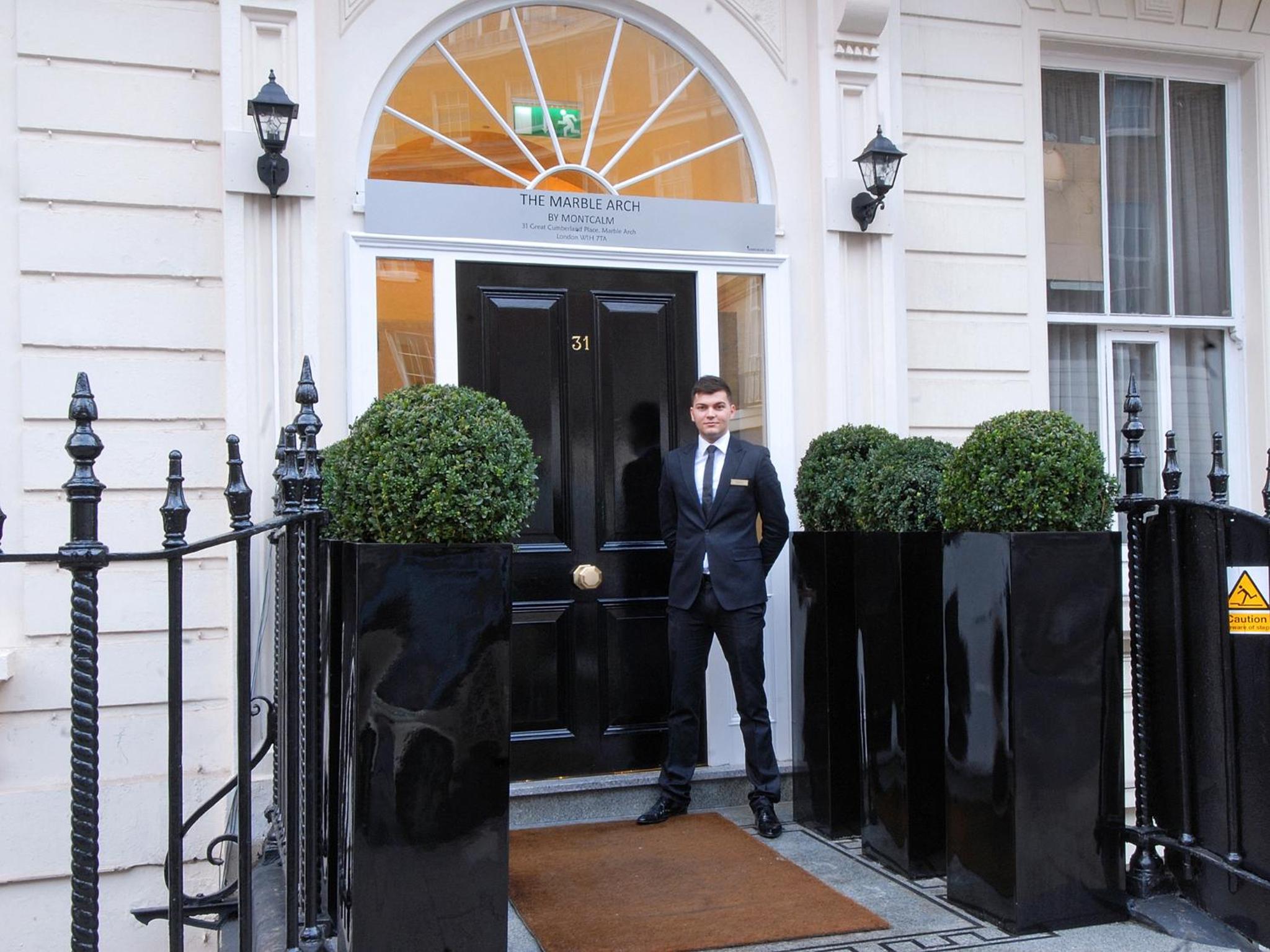 a man in a suit standing in front of a door at Park Grand Mayfair in London