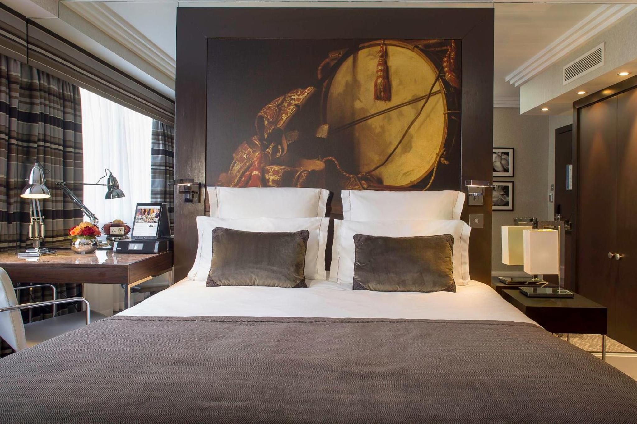 a bedroom with a large bed with a painting on the wall at The Lowndes London - A Jumeirah Partner Hotel in London