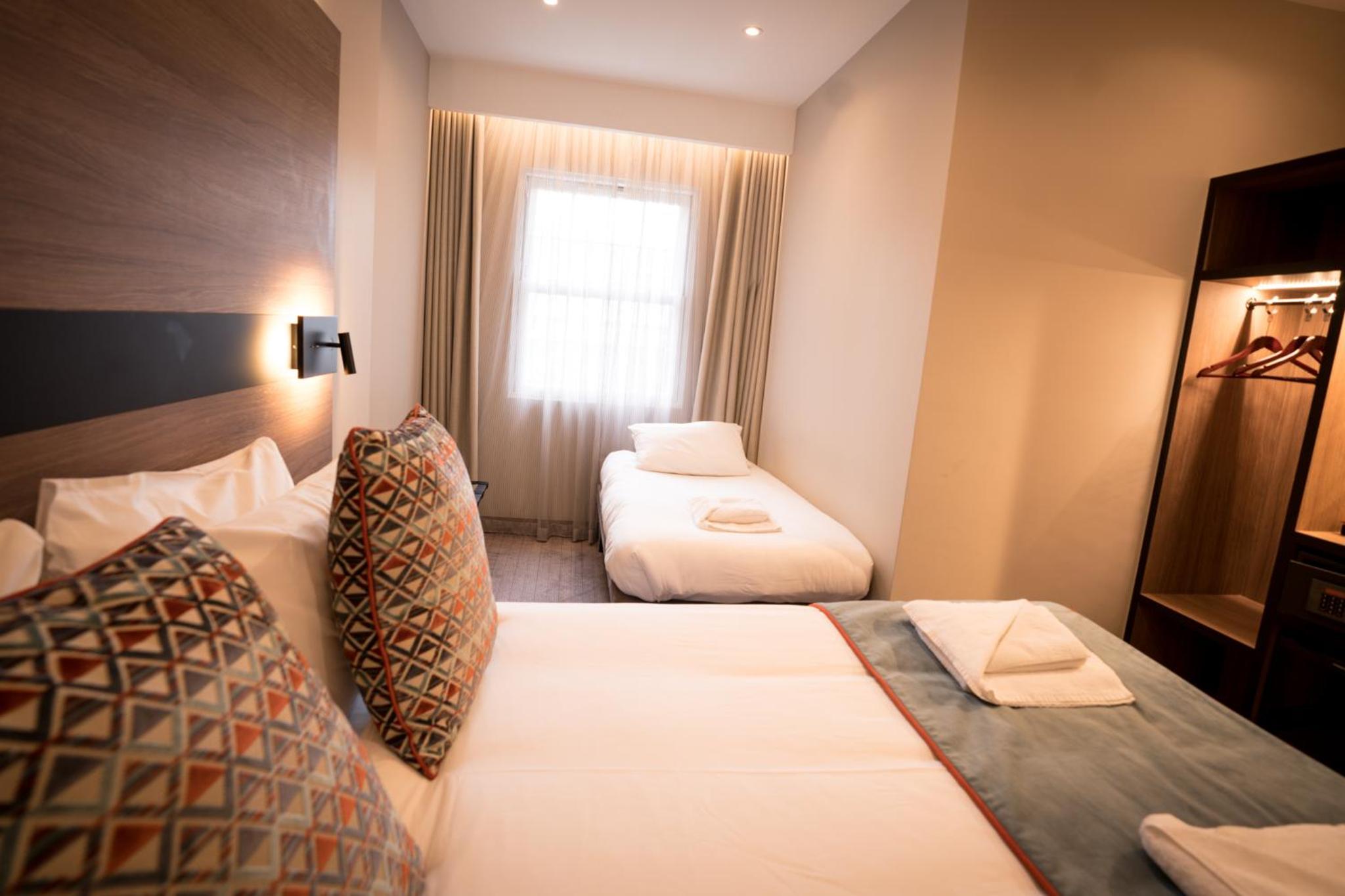 a hotel room with two beds and a window at Oxford Hotel in London